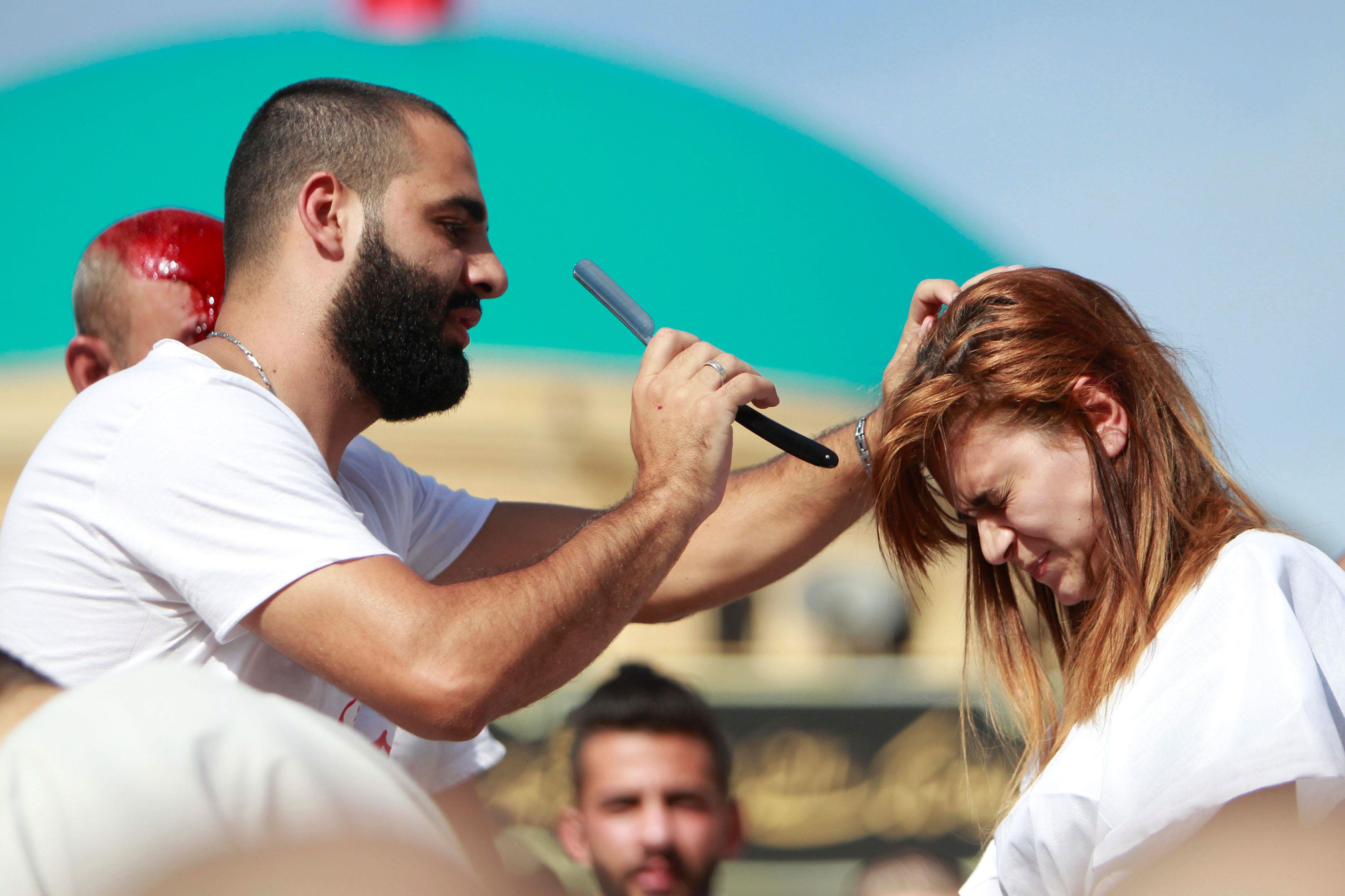 A Shi'ite Muslim attempts to tap the head of a woman with a razor to draw blood during a religious p