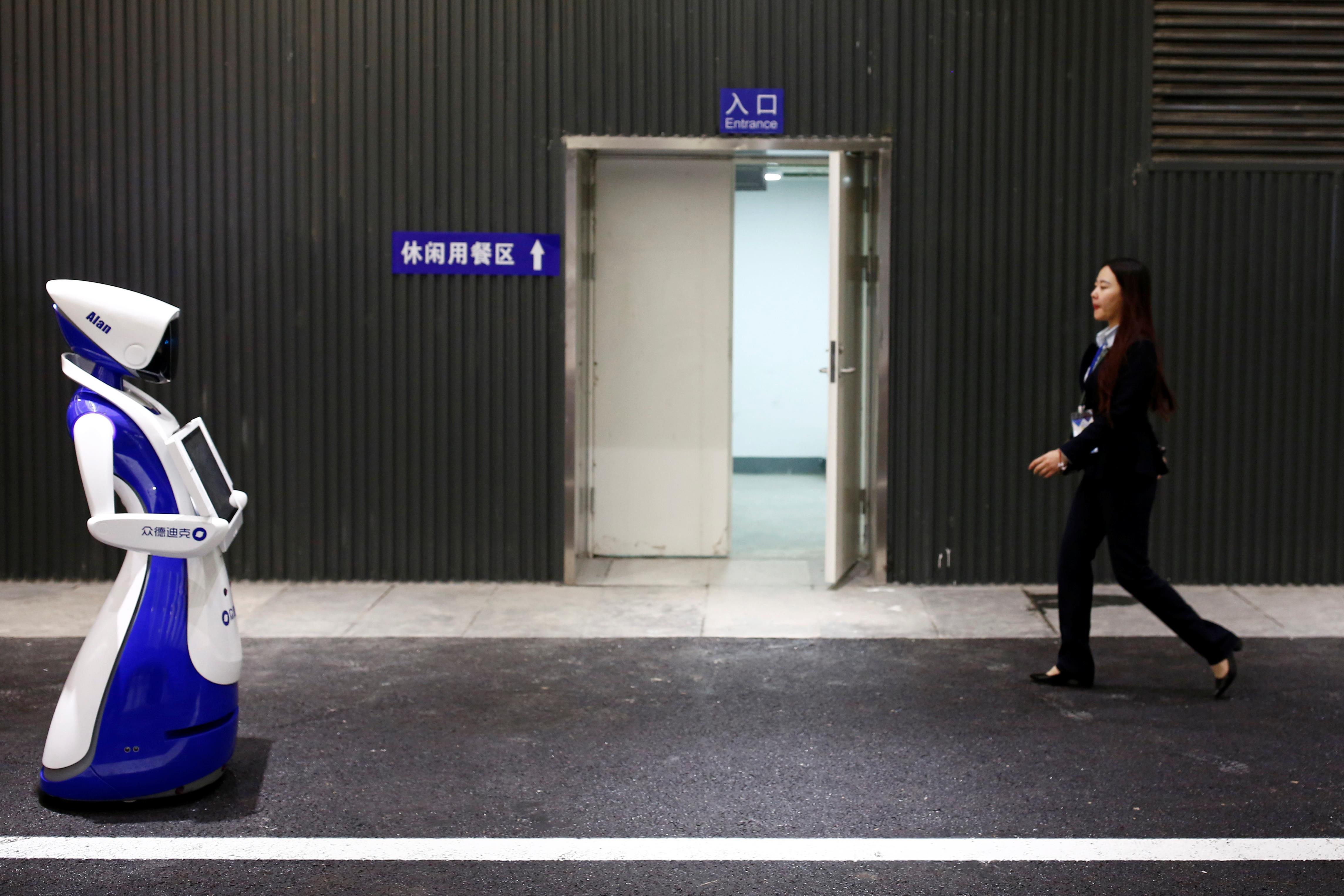 A woman walks past a robot by Robot4U Tech at the WRC 2016 World Robot Conference in Beijing.