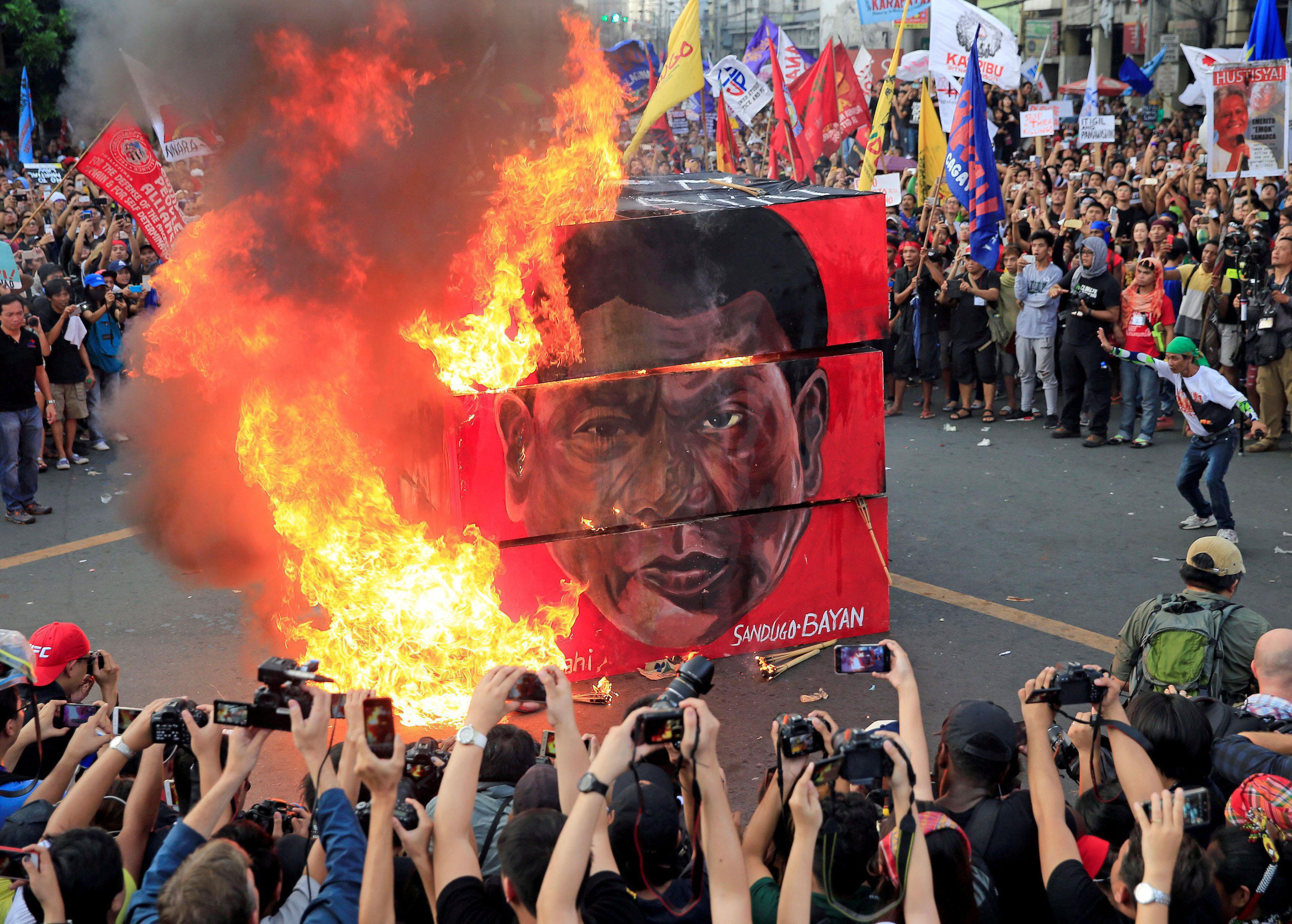 Protesters burn a cube effigy with a face of President Rodrigo Duterte during a National Day of Prot