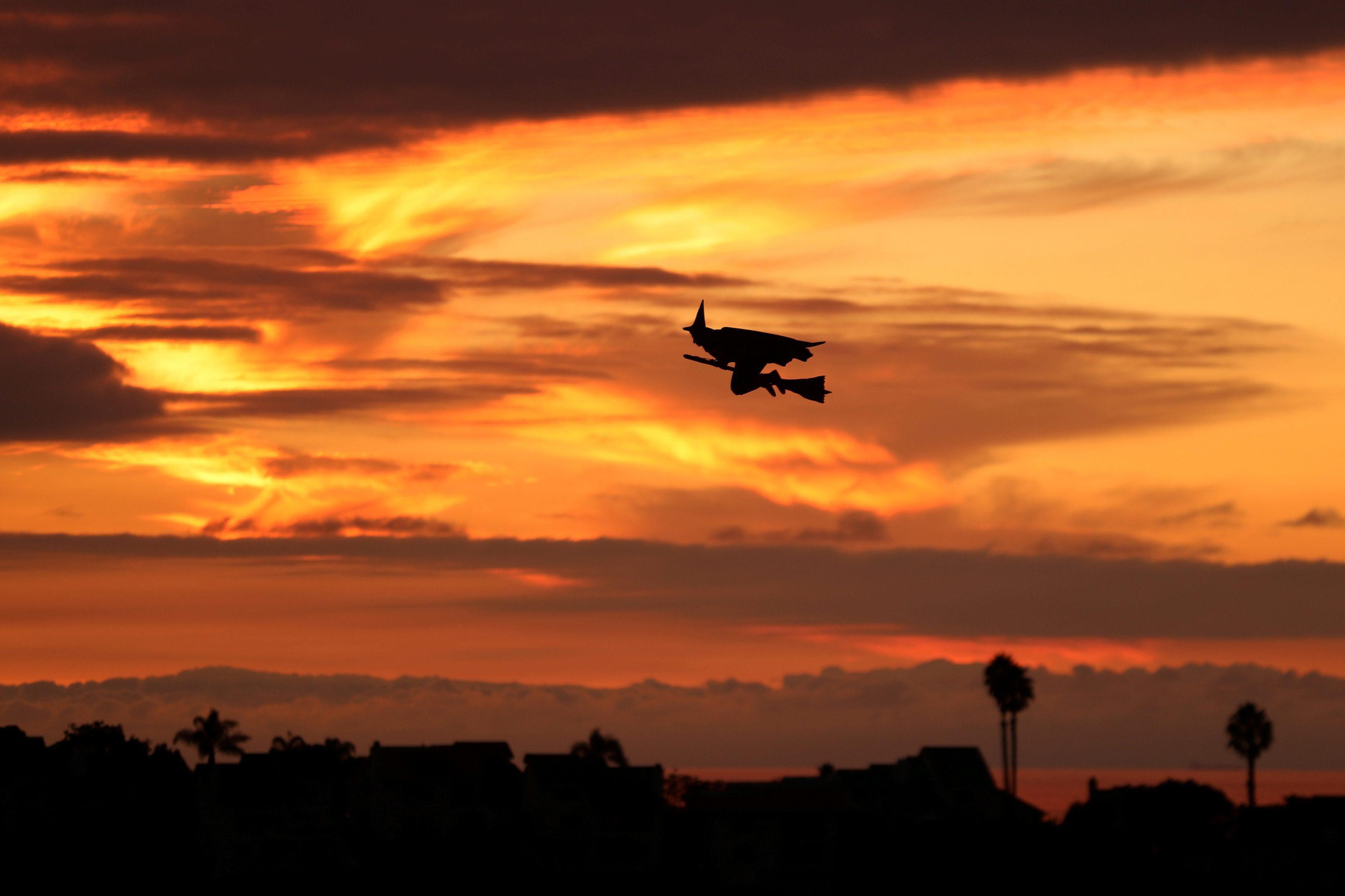 A remote controlled witch on a broom flies over a Southern California neighborhood after sunset on H