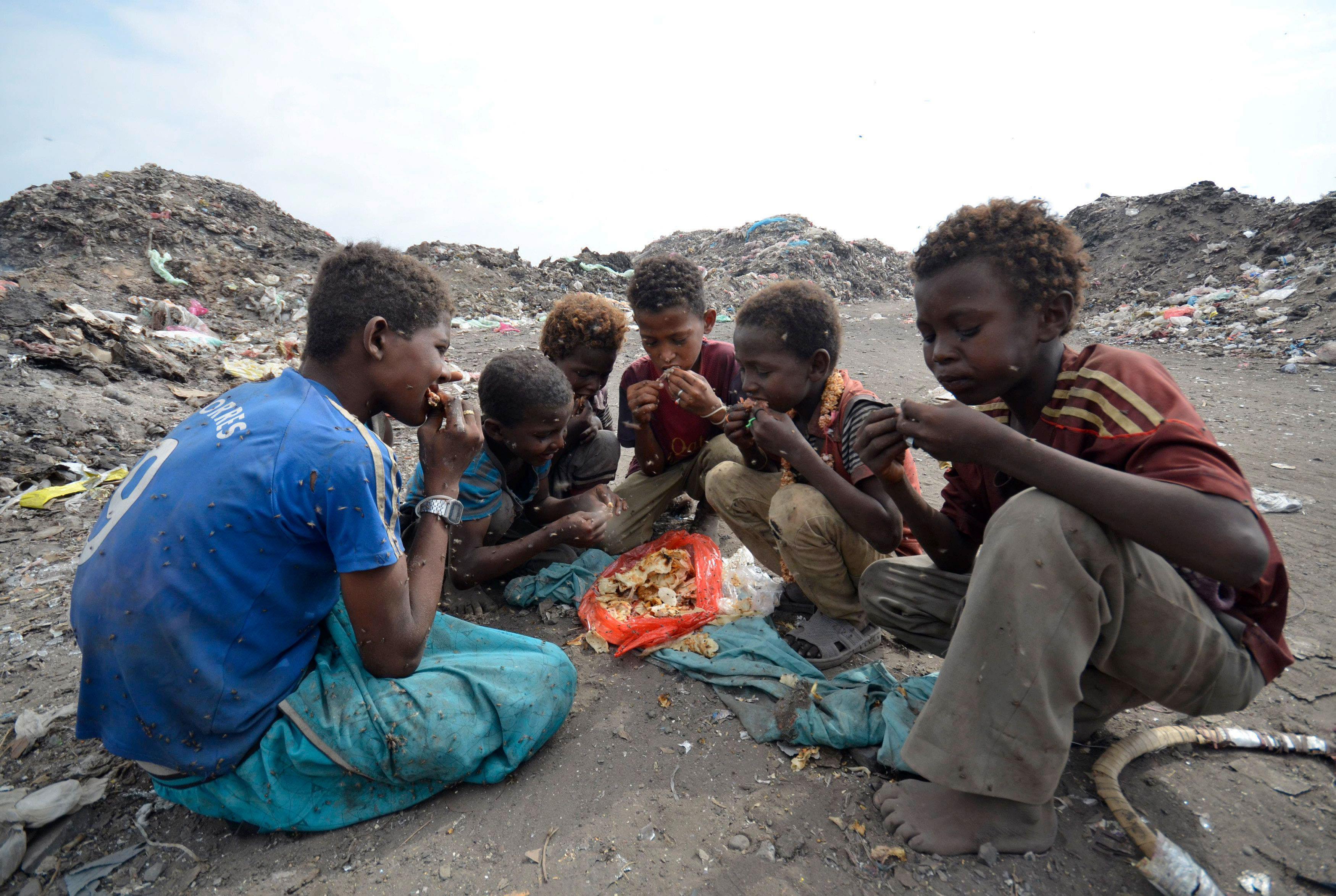Boys eat at a rubbish dump where they collect recyclable waste outside Yemen's Red Sea port city of 
