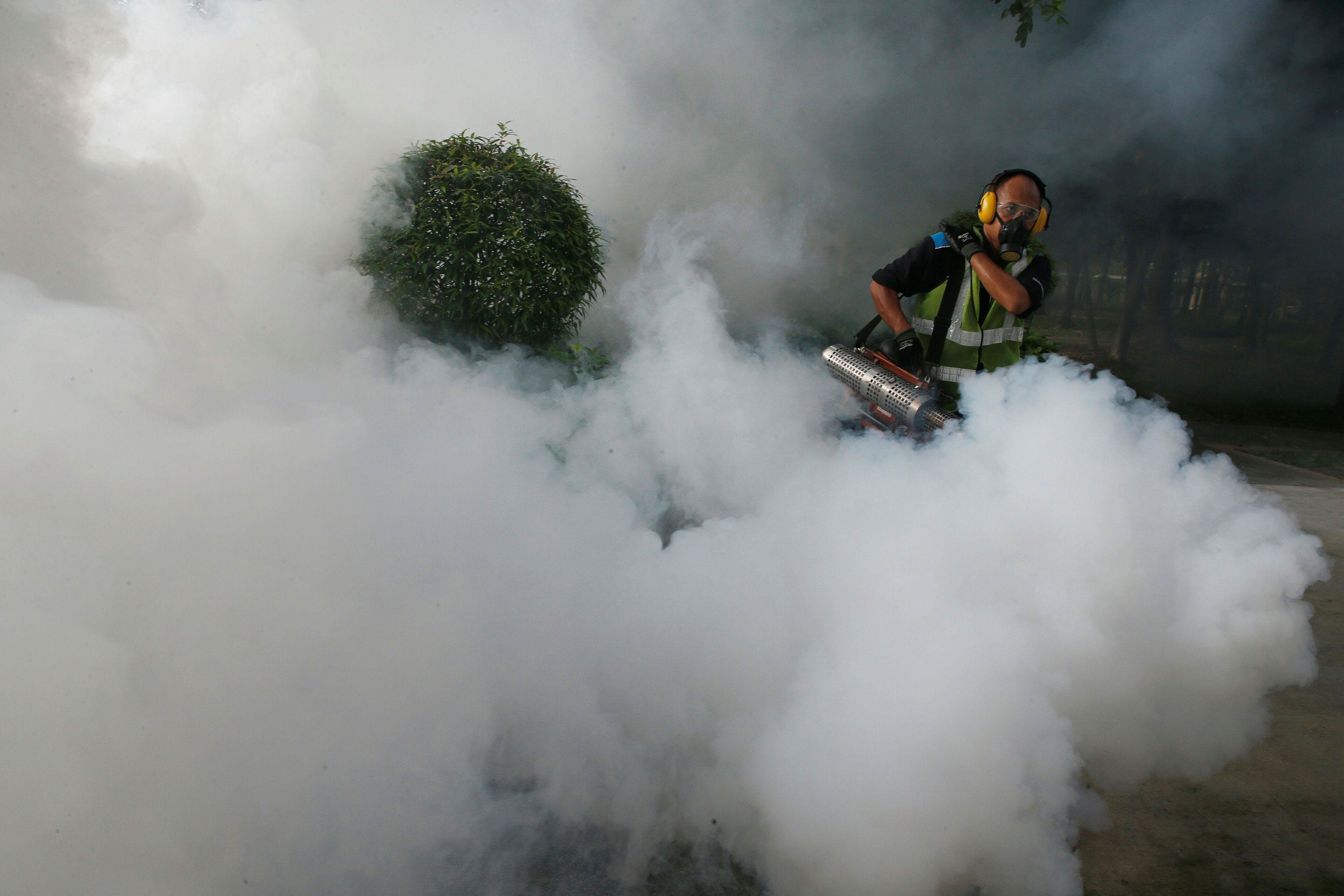 A worker fogs the common areas of a public housing estate at an area where locally transmitted Zika 