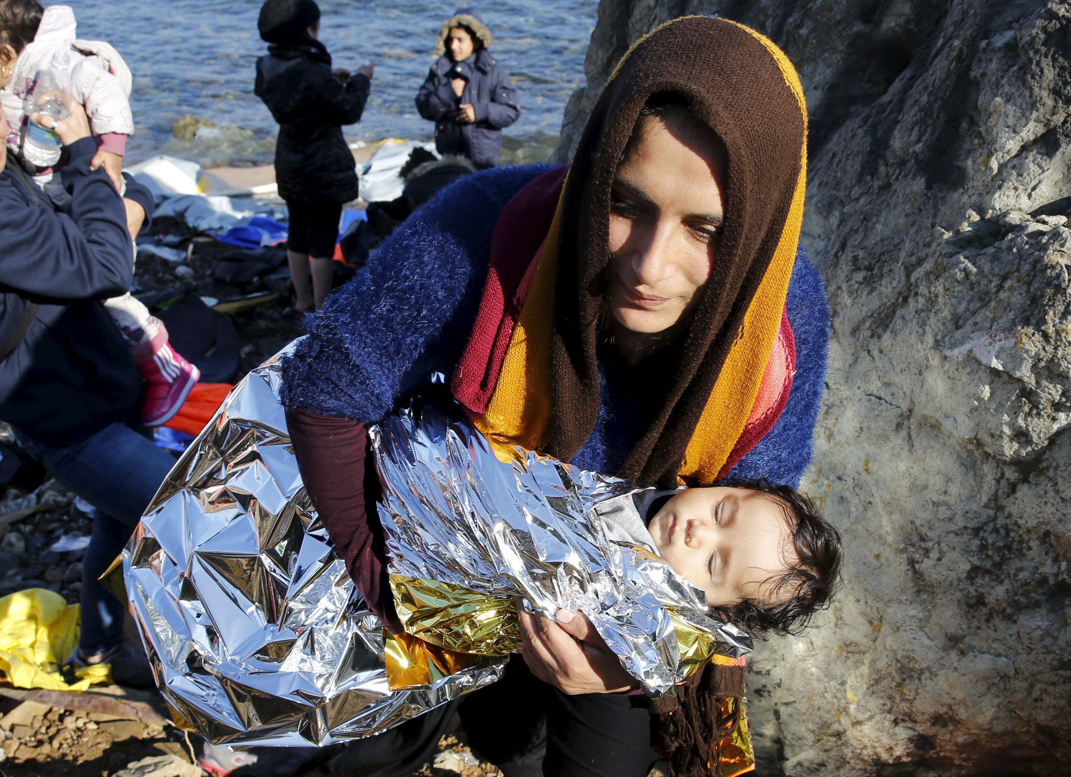 An Afghan migrant carries her baby after arriving by a raft on the Greek island of Lesbos