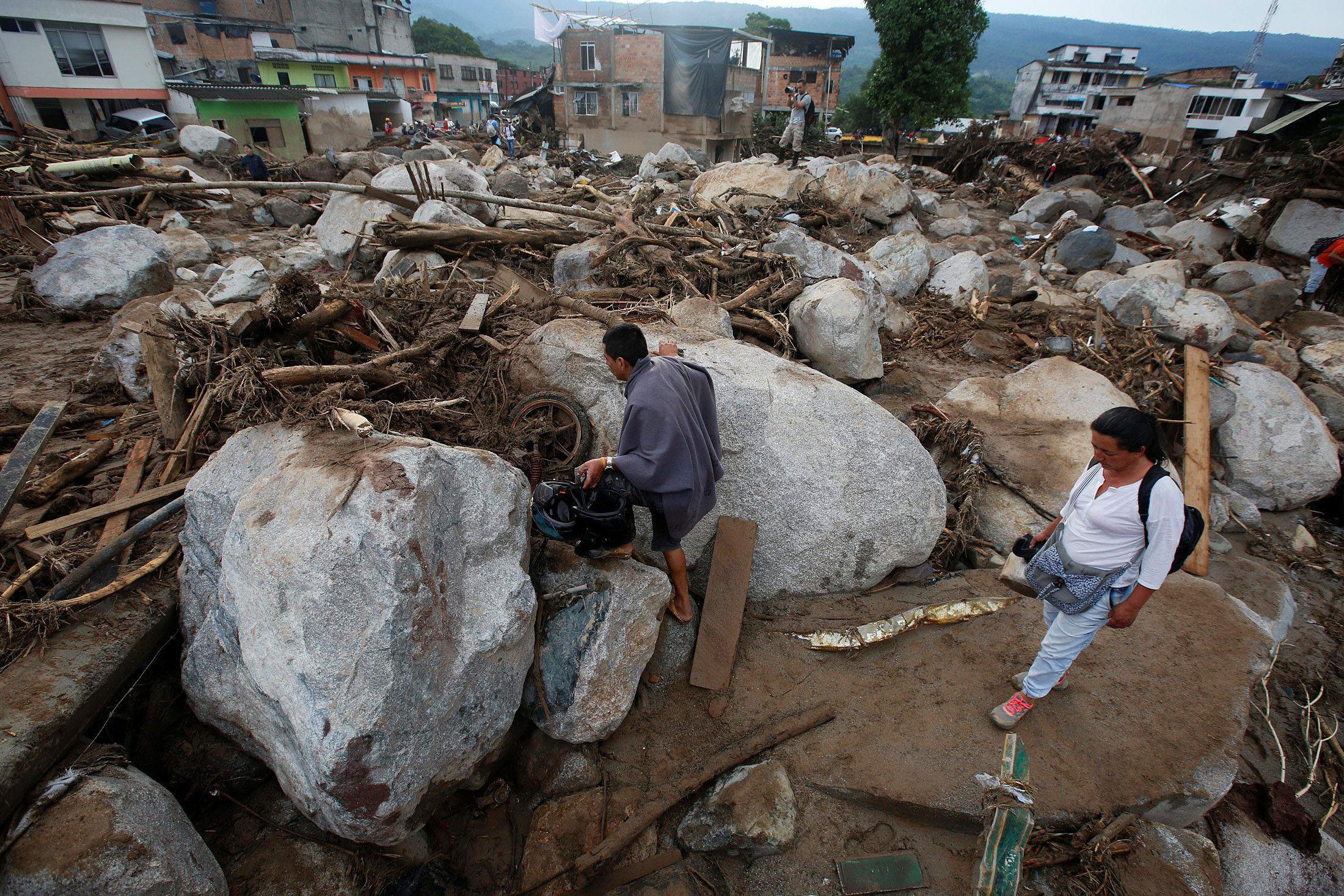 People walk on a street destroyed after flooding and mudslides, caused by heavy rains leading severa