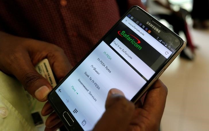 An employee assists a customer to set-up M-Pesa money transfer servive on his handset inside a mobile phone care centre operated by Kenyan's telecom operator Safaricom; in the central business district of Kenya's capital Nairobi, May 11, 2016. REUTERS/Thomas Mukoya
