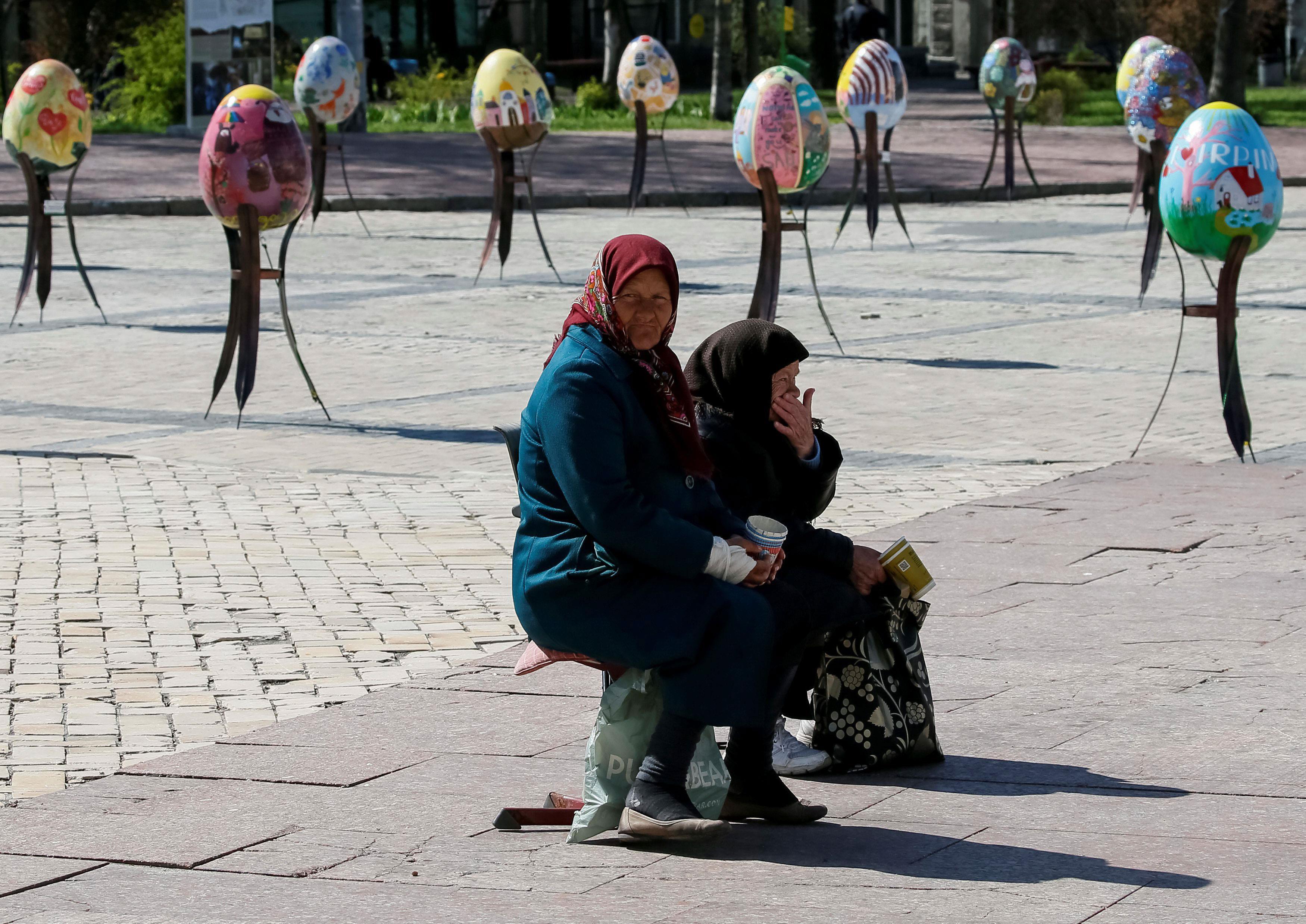 Elderly women beg for money near traditional Ukrainian Easter eggs 