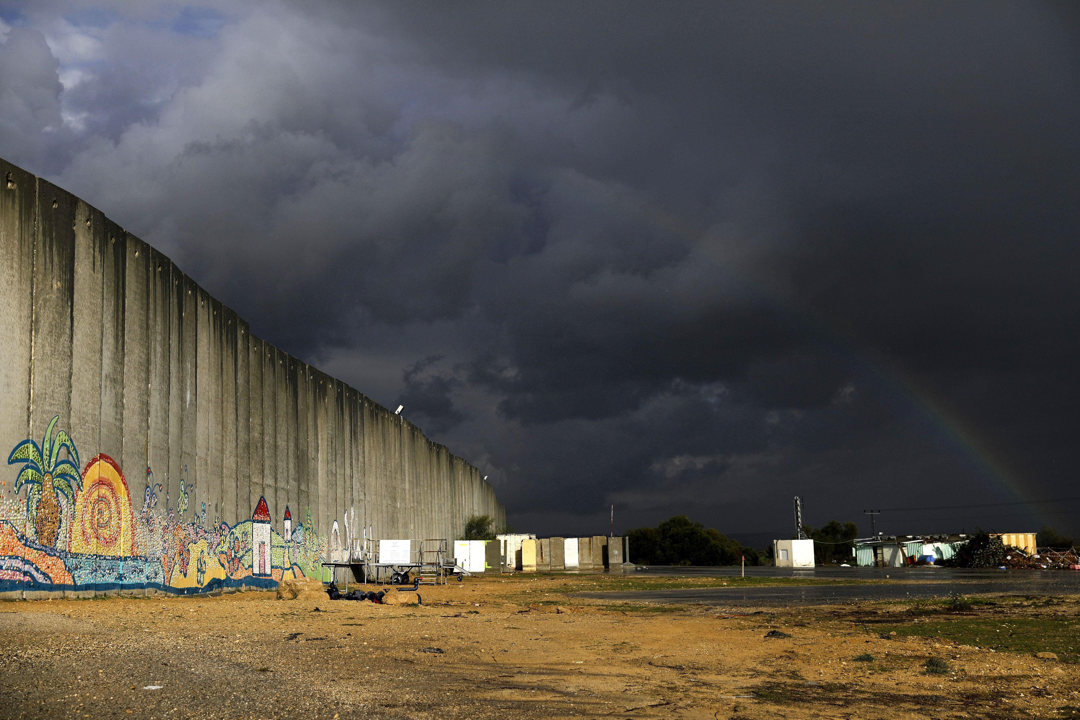 A rainbow is seen over a concrete barrier in Netiv Haasara, southern Israel