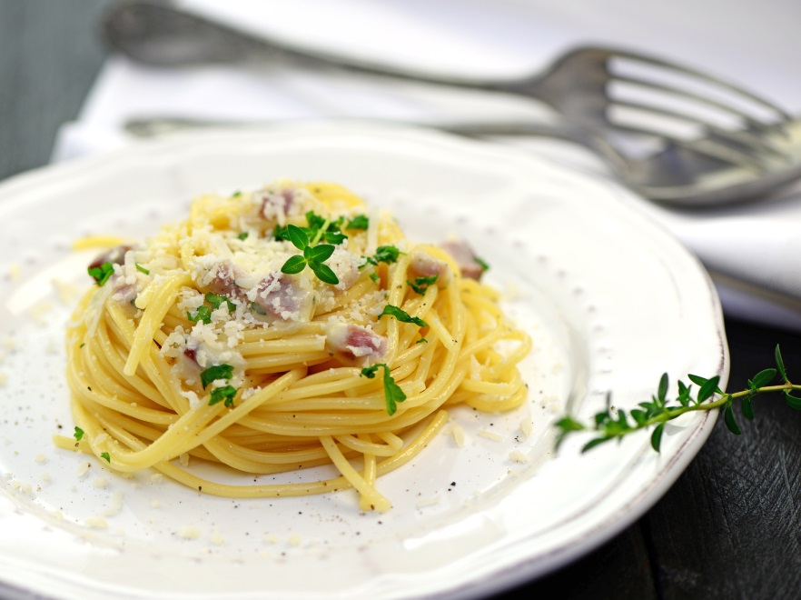 SPAGHETTI CARBONARA Składniki: • Międzybrodzki Makaron spaghetti – 500 g • Wędzony boczek – 250 g • Śmietana 30 % – 250 ml • 3 żółtka • Starty żółty ser – 2 łyżki • Czosnek – 1 ząbek • Cebula – 1 szt. • Sól, pieprz, bazylia