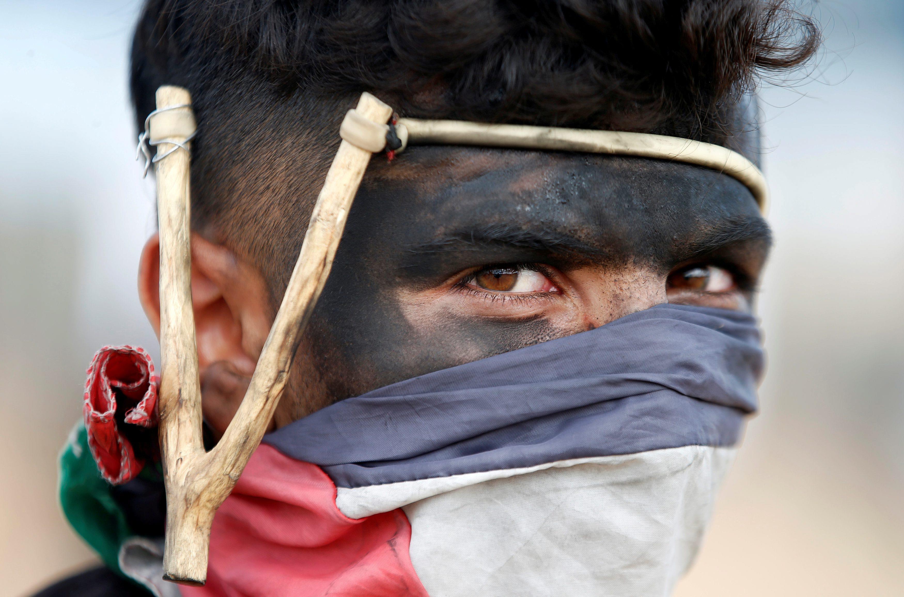 Palestinian demonstrator with a slingshot looks on during a protest against U.S. embassy move to Jer