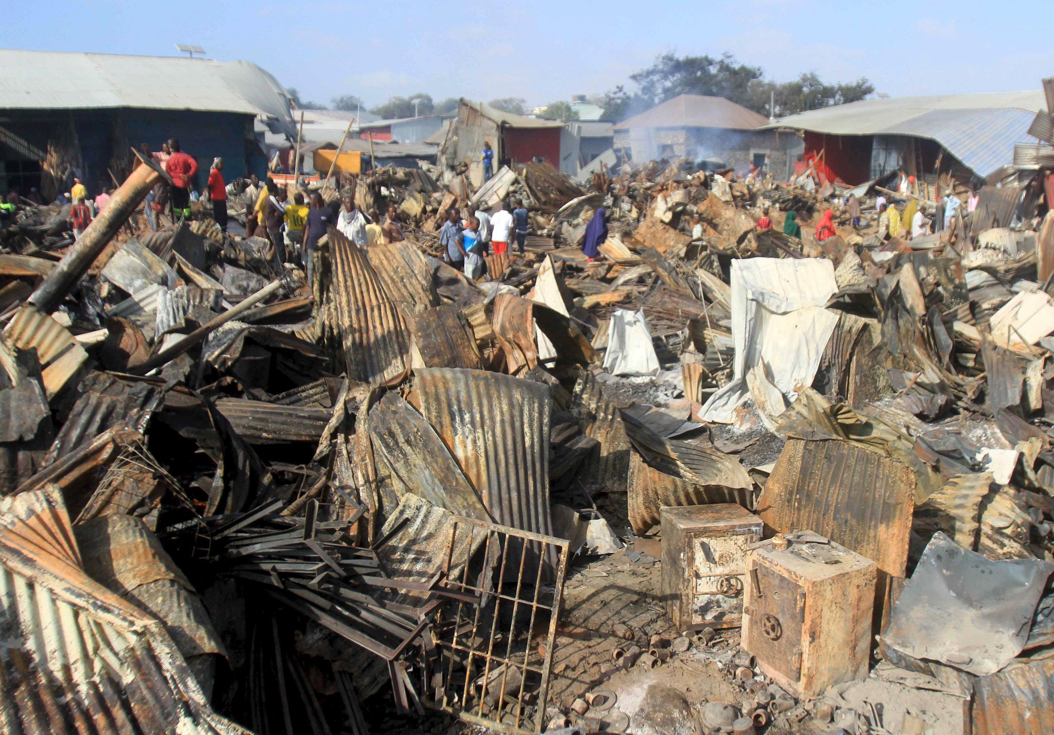 Twisted iron roofing is seen in the foreground after a night fire razed down a busy market in Mogadi