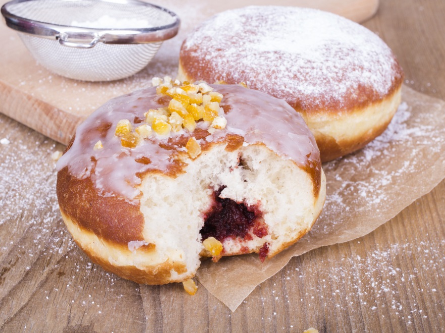 SKŁADNIKI: • 250 ml mleka • 14 g suchych drożdży • 3 łyżki cukru • 500 g mąki pszennej tortowej • 200 g żurawiny suszonej Bakalland • 2 szklanki soku pomarańczowego • 100 g skórki pomarańczowej Bakalland • szczypta soli • 5 g cukru wanilinowego • 1 jajko • 4 żółtka • 50 g masła • 2 łyżki spirytusu PRZYGOTOWANIE W rondelku podgrzewamy mleko. Przelewamy je do miski, dodajemy drożdże, 1 łyżkę mąki oraz 1 łyżkę cukru. Mieszamy i wstawiamy miskę do garnka z ciepłą wodą. Odstawiamy na ok. 15 minut. W tym czasie przesiewamy pozostałą mąkę, dodajemy szczyptę soli i cukier wanilinowy. Dodajemy wyrośnięte drożdże, wszystko mieszamy. Jajko i żółtka ucieramy z pozostałym cukrem na puszystą pianę, dodajemy do wszystkich zmieszanych produktów. Następnie dokładnie wyrabiamy ciasto. Do gotowego ciasta dodajemy roztopione i wystudzone masło oraz spirytus. Zagniatamy dokładnie ciasto, tak aby wszystkie składniki się połączyły. Przykrywamy ściereczką odstawiamy w ciepłe miejsce do wyrośnięcia, aż masa znacznie zwiększy swoją objętość. W tym czasie zalewamy żurawinę sokiem pomarańczowym. Odstawiamy na 15 minut, następnie dodajemy pół szklanki wody i gotujemy wszystko na małym ogniu przez ok. 20 minut. Po ugotowaniu miksujemy blenderem, odstawiamy do wystudzenia. Gotowe, wyrośnięte ciasto wykładamy na lekko posypaną mąką stolnicę i wygniatamy przez ok. 3 minuty. Wałkujemy na nieduży placek i za pomocą szklanki wycinamy kółka. Czynność w razie potrzeby powtarzamy. Wycięte krążki rozkładamy na stolnicy, przykrywamy ściereczką i odstawiamy do wyrośnięcia. Następnie każdy krążek delikatnie rozpłaszczamy w dłoni i w środek kładziemy łyżeczkę dżemu żurawinowego. Zlepiamy boki i formujemy kulkę. Rozgrzewamy olej i wkładamy do niego wyrośnięte pączki. Smażymy ok. 2 minuty z każdej strony. Ciepłe pączki maczamy w lukrze. Na lukier sypiemy skórkę pomarańczową.