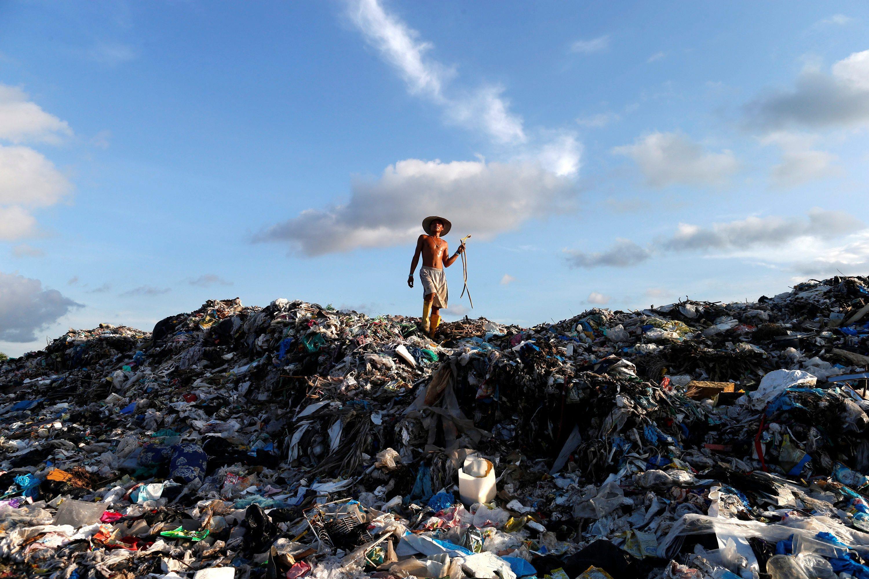 A man walks on the top of the huge dump as he looks for fire-wood outside Yangon