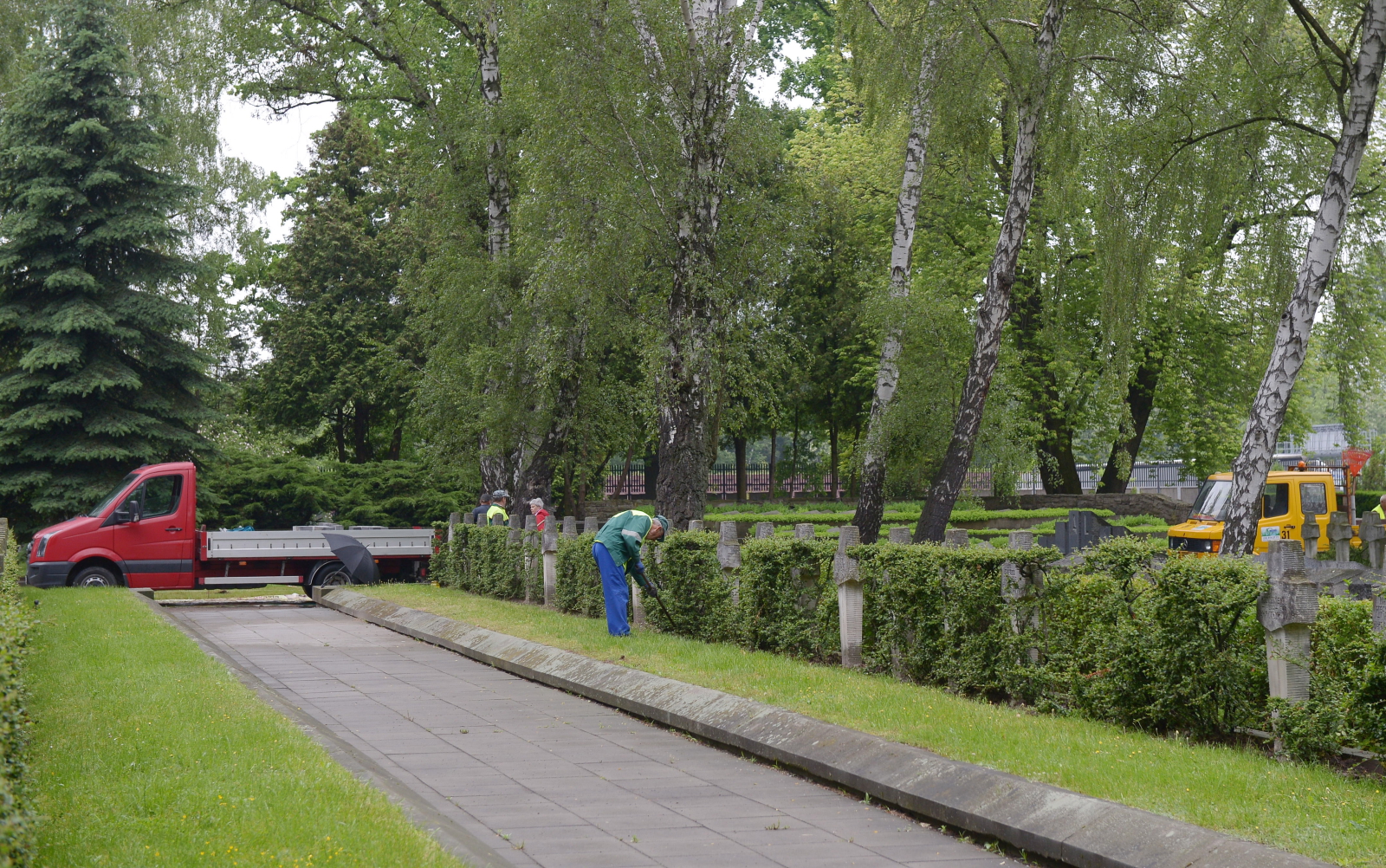 Trwają przygotowania do pogrzebu - pracownicy miejskich służb ustawiają taśmy odgradzające na trawnikach, przycinają krzewy, porządkują okolicę