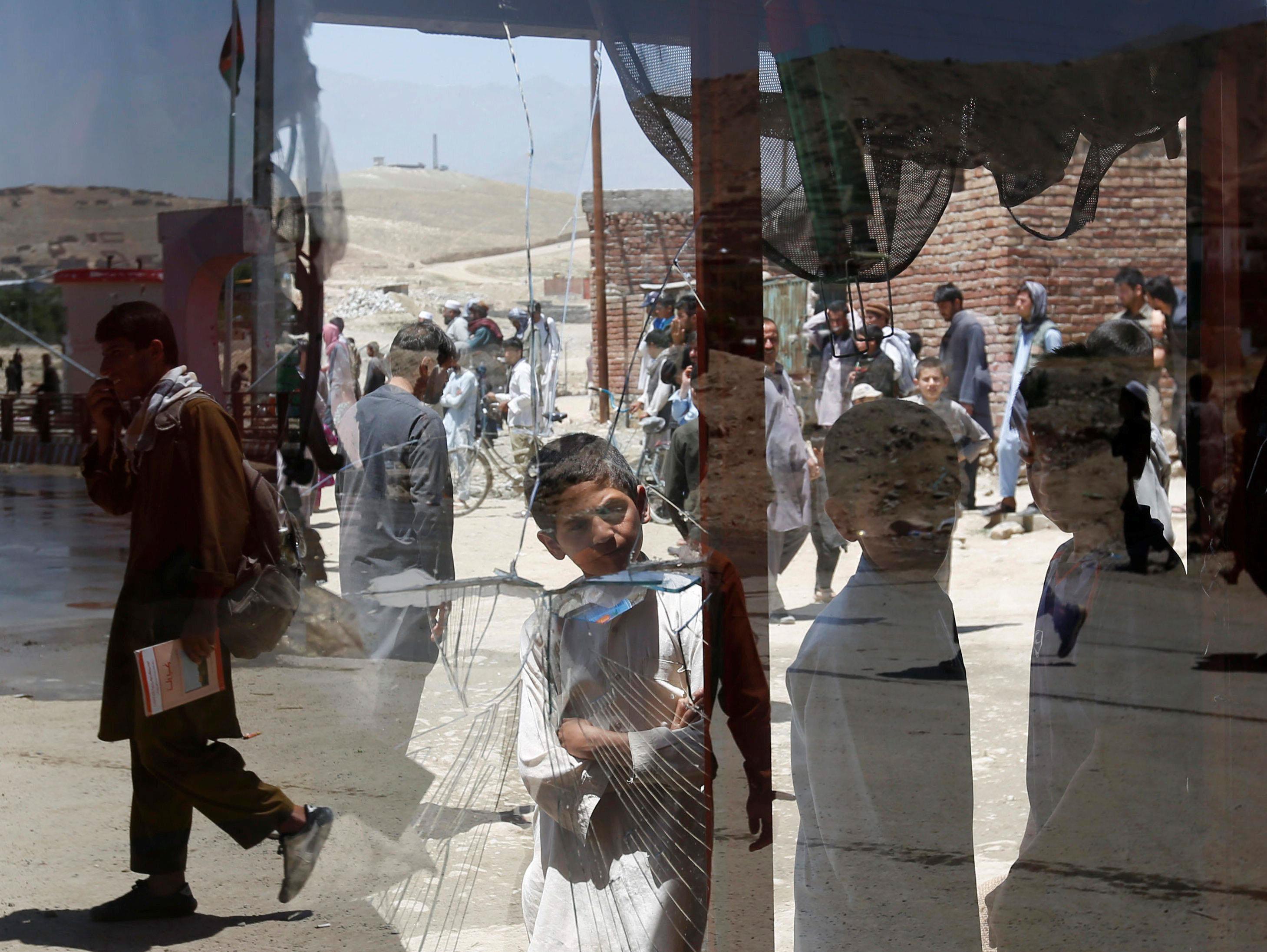 Afghan boys look a damaged window of a shop after a suicide attack in west of Kabul, Afghanistan