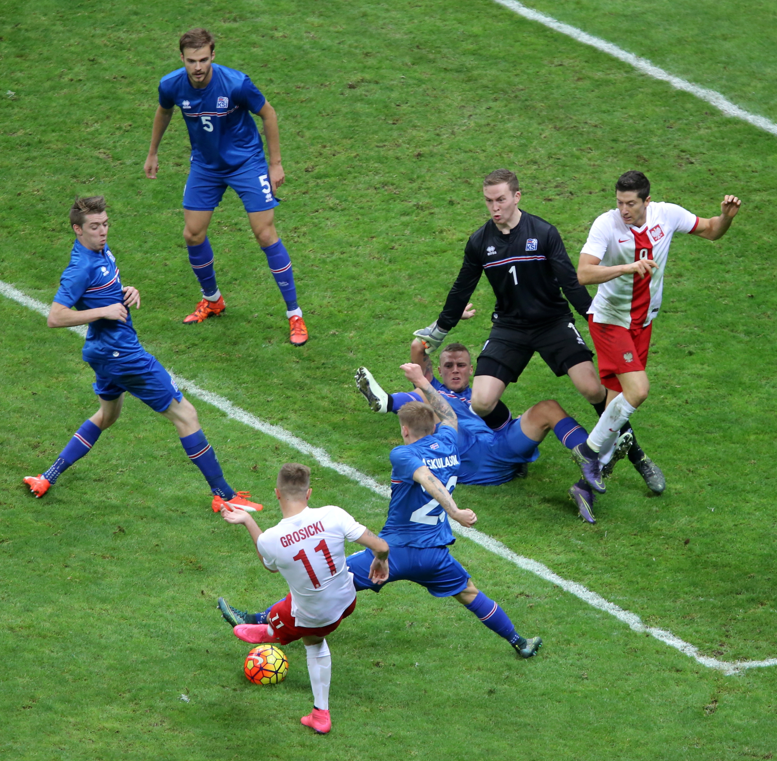 Kamil Grosicki (#11) walczy o piłkę z Islandczykiem Ari Freyrem Skulasonem (P) podczas meczu towarzyskiego w Warszawie, 13 bm. Obok bramkarza Oegmundur Kristinsson (#1) stoi Robert Lewandowski (P)