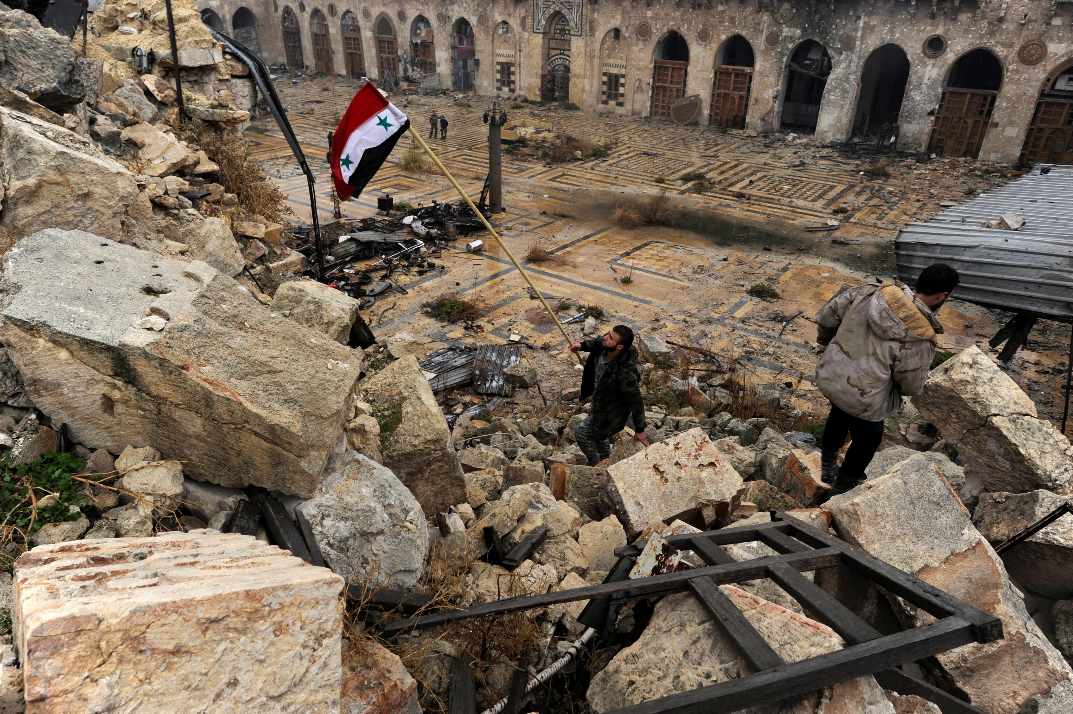 A member of forces loyal to Syria's President Bashar al-Assad attempts to erect the Syrian national 