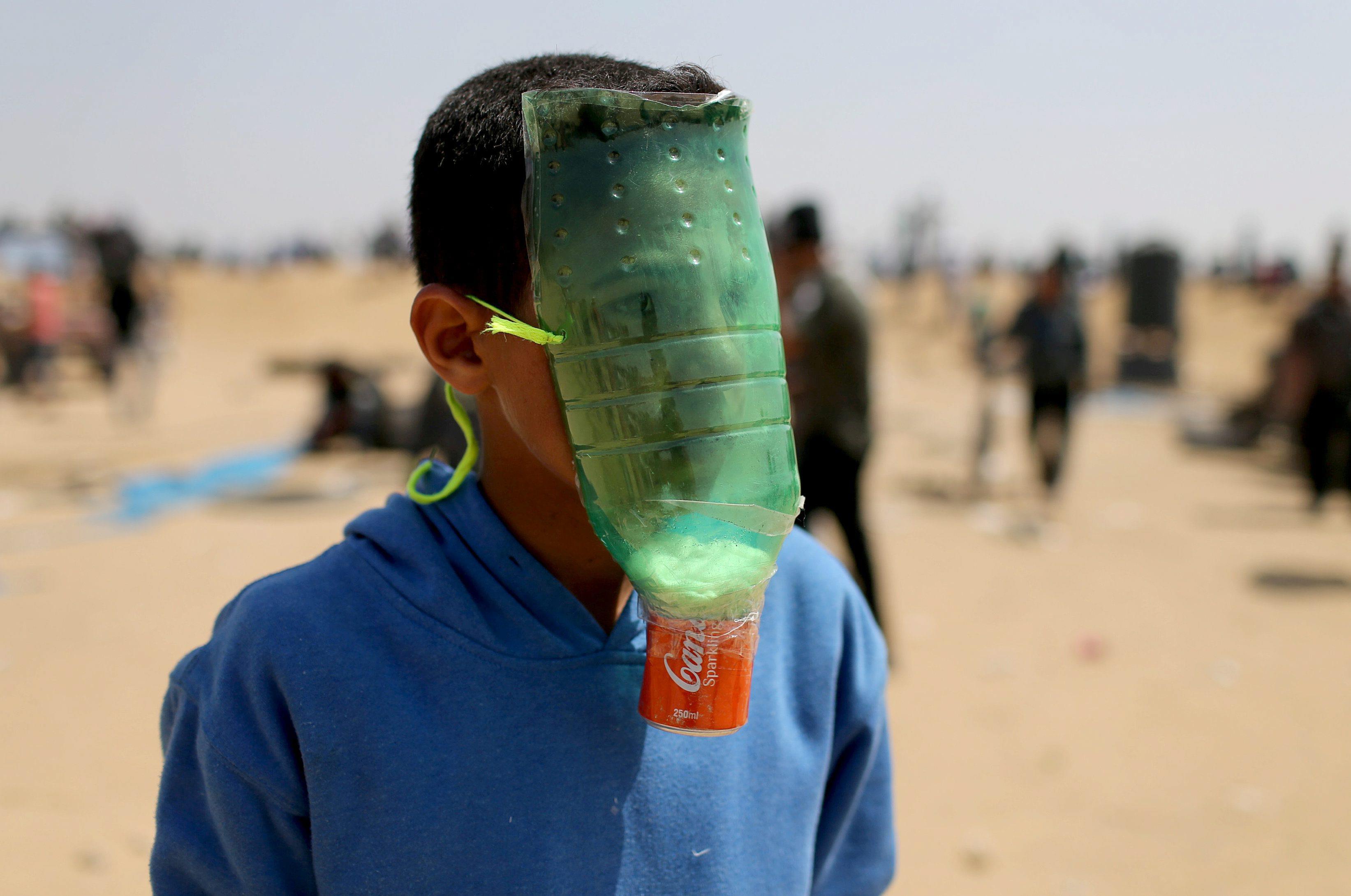 Palestinian protects himself from inhaling tear gas at the Israel-Gaza border during a protest deman