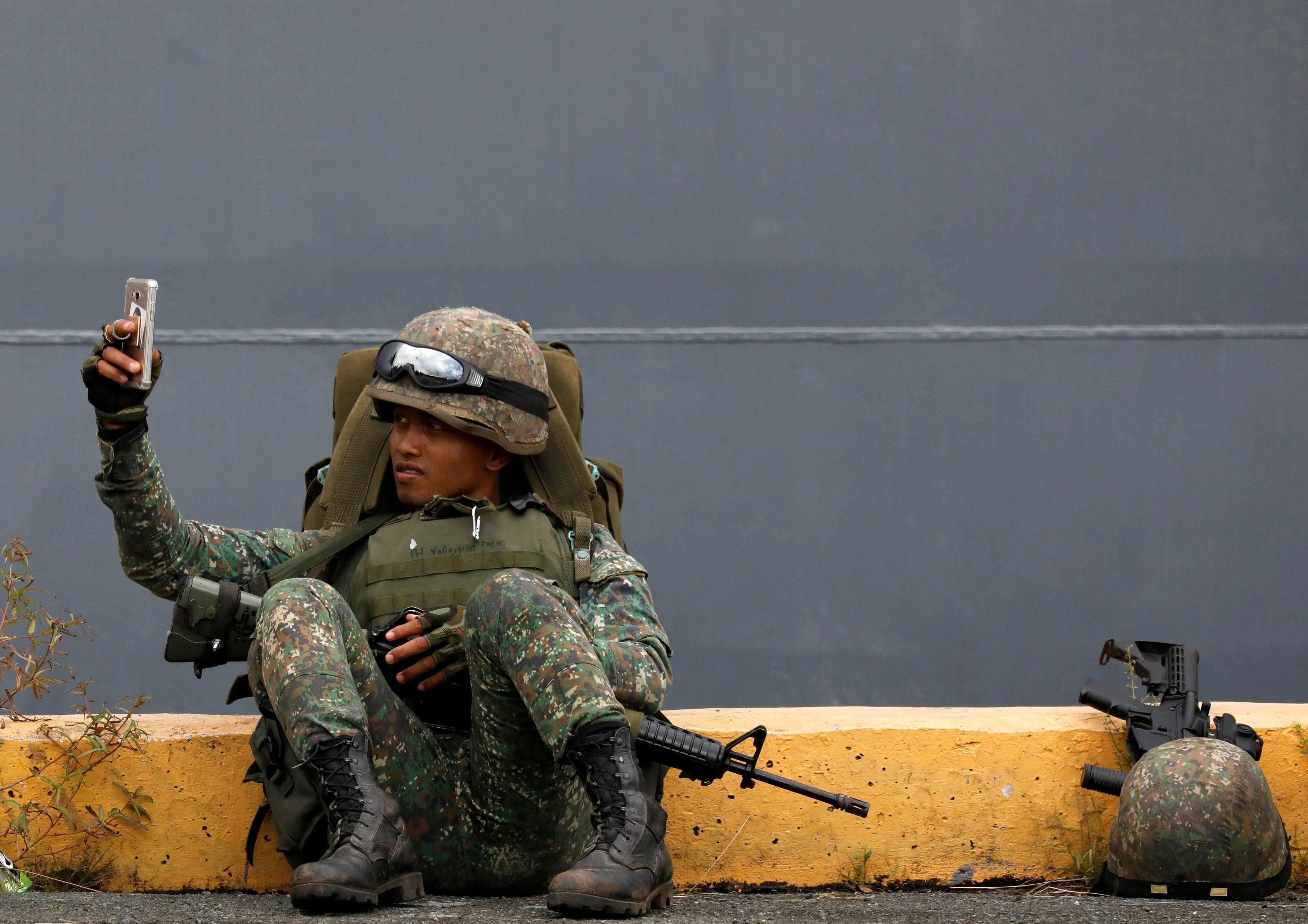 A Philippine marine soldier takes a selfie with his phone during their arrival from Marawi at port a