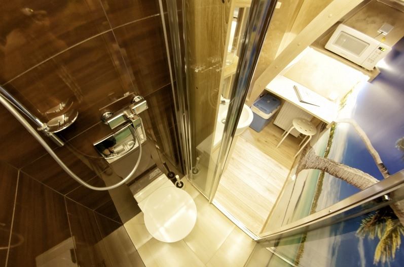 Najmniejszy apartament świata – jak jest urządzony? Do dyspozycji gości są: kabina prysznicowa z toaletą, aneks kuchenny i łóżko na antresoli. Brakuje otwieranego okna – zamiast niego są mleczne przeszklenia w suficie. - Byliśmy pełni obaw, jak przyjmie się nasz 2,5-metrowy lokal, tym bardziej że już od początku pomysł wydawał się z kosmosu. Architekt, dostając zlecenie, aż zaniemówił ze zdziwienia. Ale popularność apartamentu przerosła nasze oczekiwania. Klienci dokonują rezerwacji z dużym, niekiedy kilkumiesięcznym wyprzedzeniem - mówi opiekun lokalu, Filip Różański w rozmowie z LifeinKrakow.pl.
