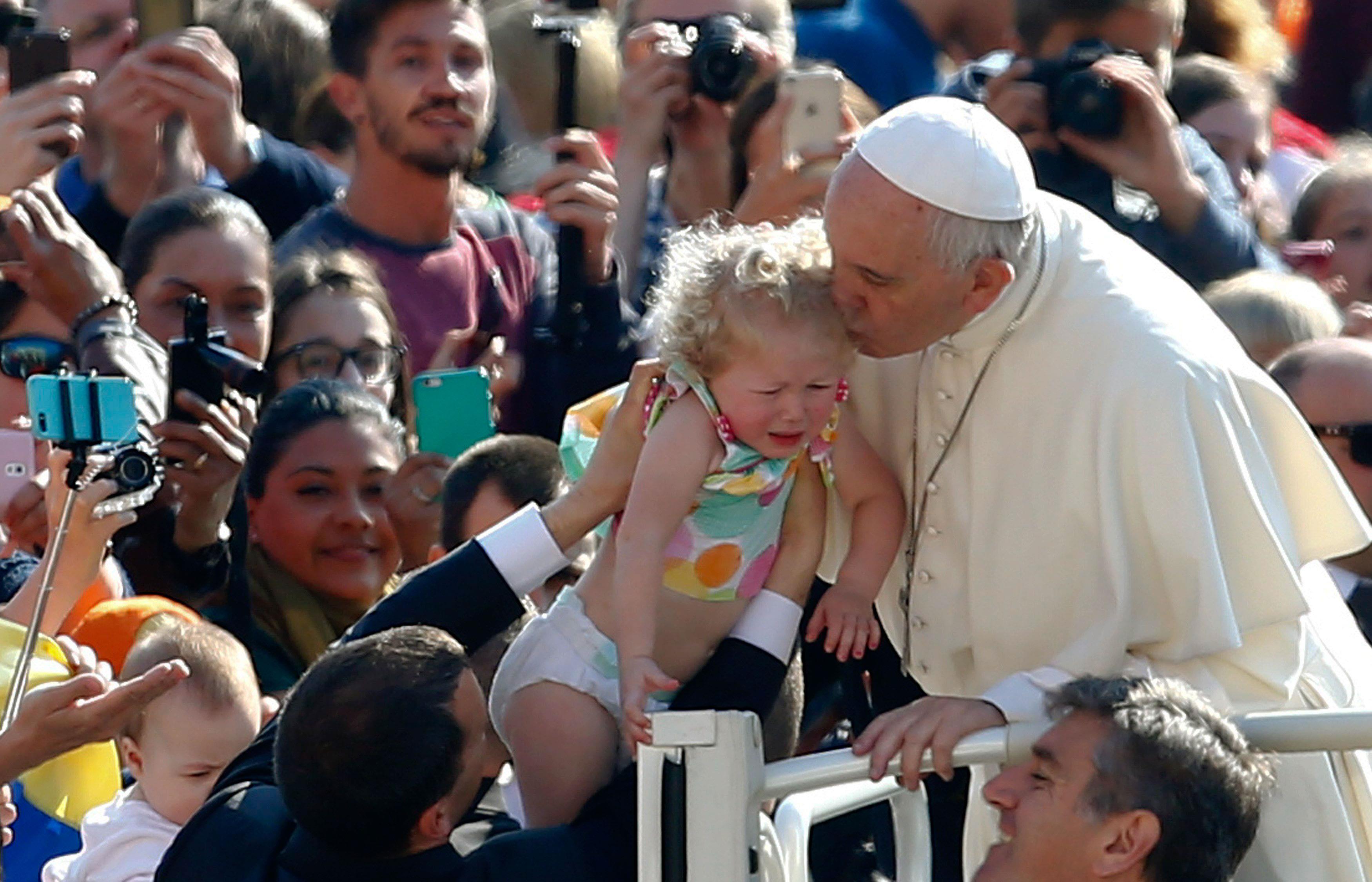 Pope Francis kisses a child as he leads the weekly general audience in Saint Peter's Square at the V