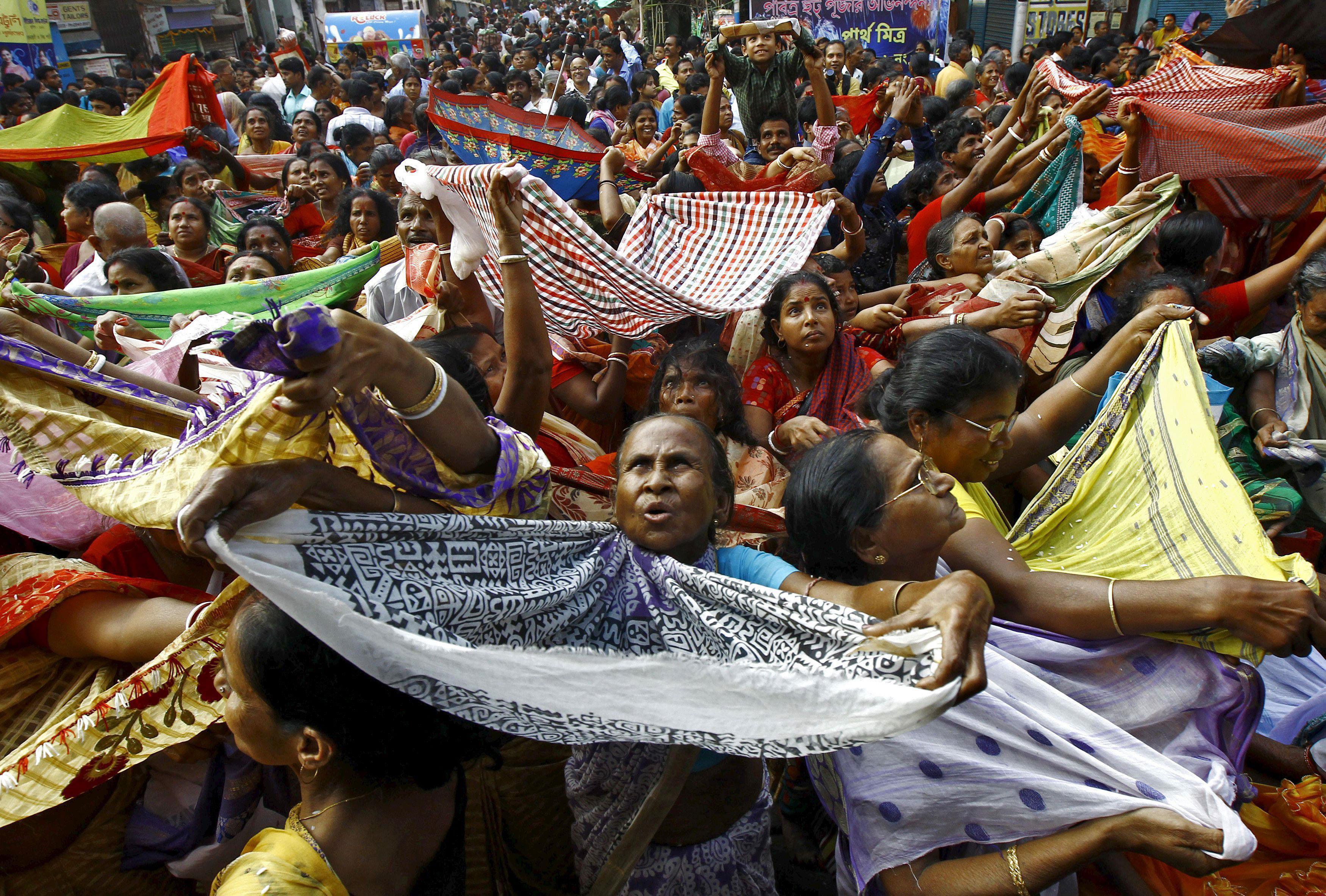 Hindu devotees hold up scarves to receive rice as offerings being distributed by the temple authorit