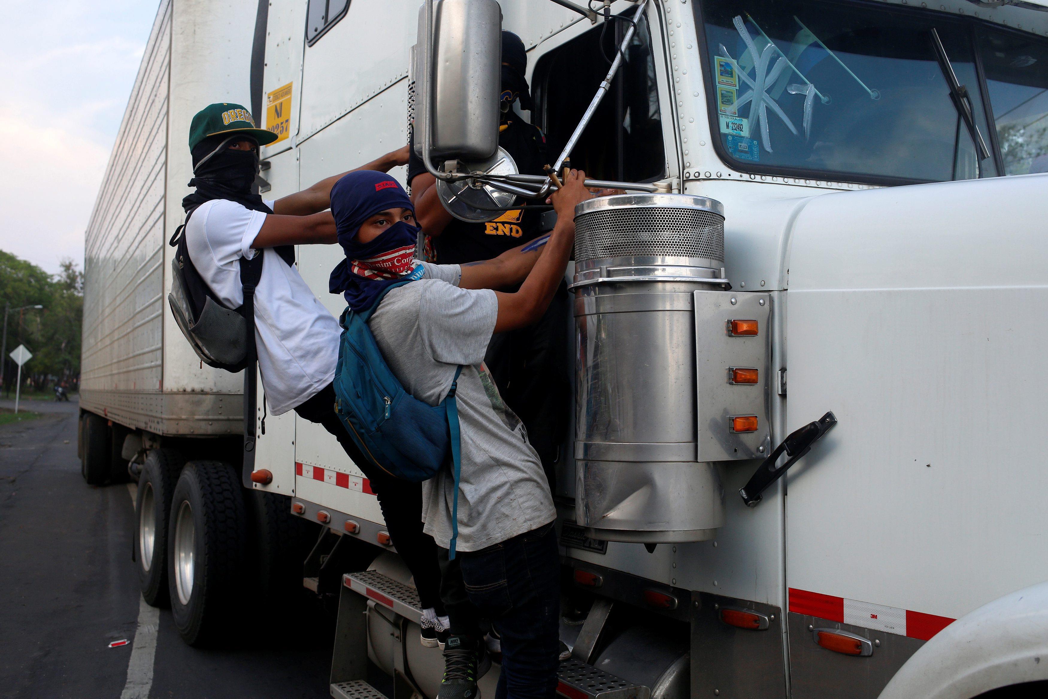 Protesters hang from the side of a truck during a protest against President Daniel Ortega's governme