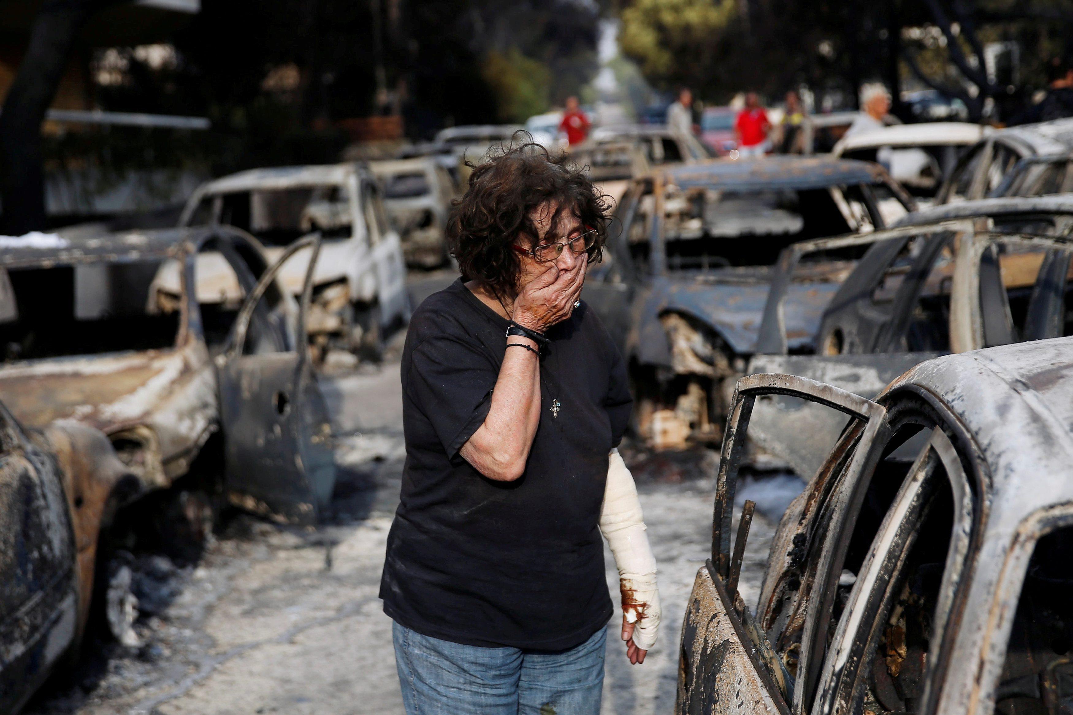 A woman reacts as she tries to find her dog, following a wildfire at the village of Mati, near Athen