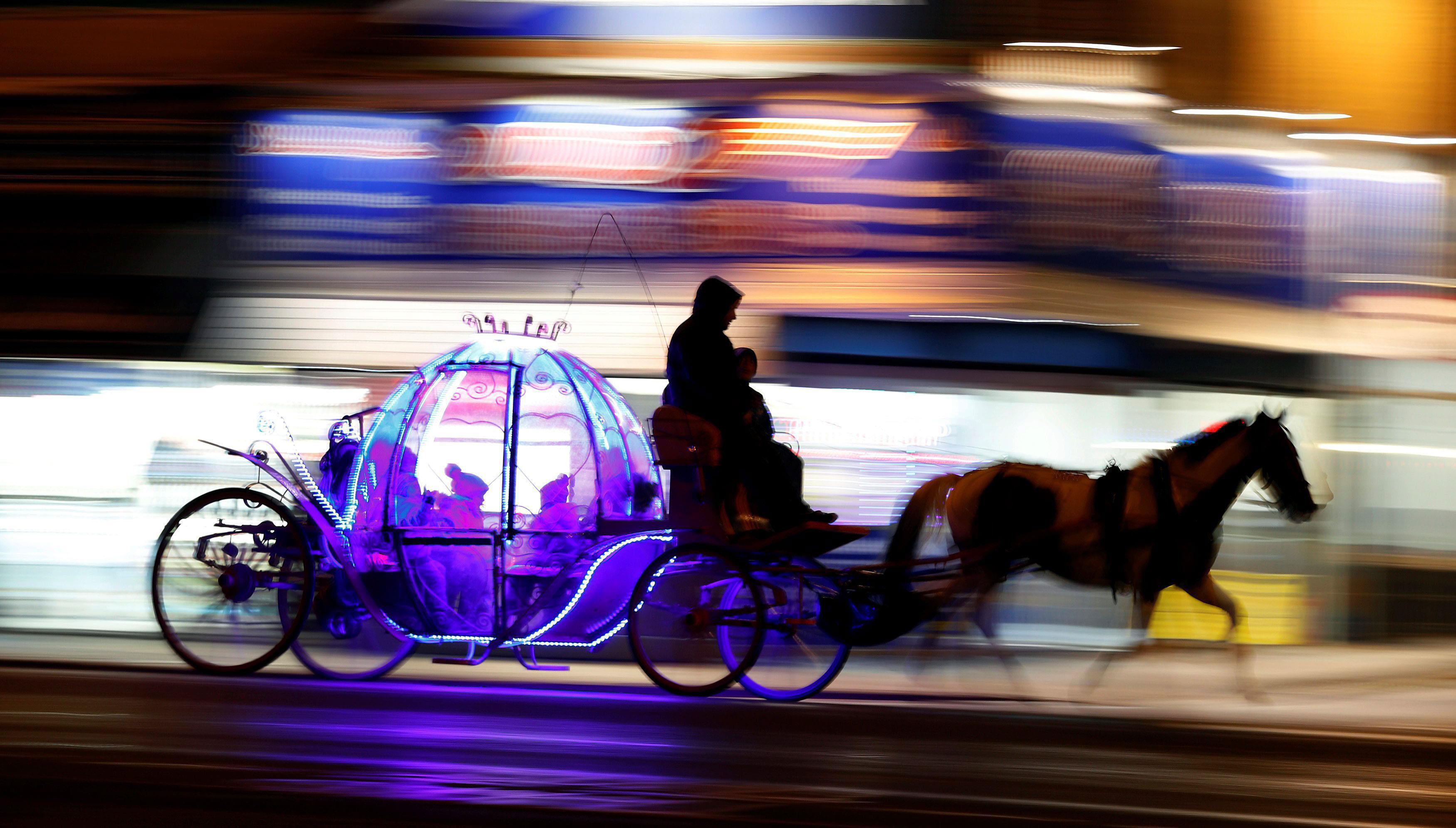 Children travel on an illuminated horse drawn carriage as they pass under the illuminations on the p