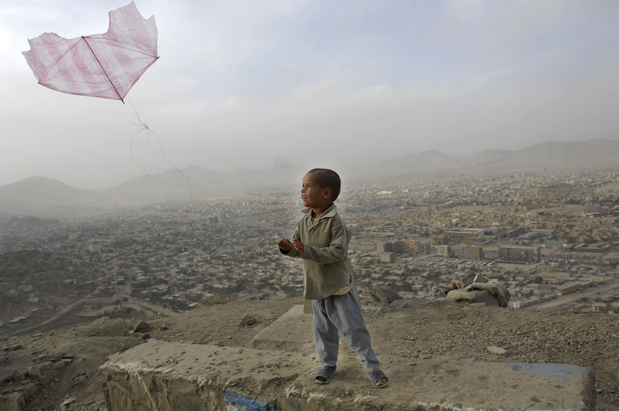 Kabul. Mały chlopiec puszcza latawiec zrobiony z foliowej torby