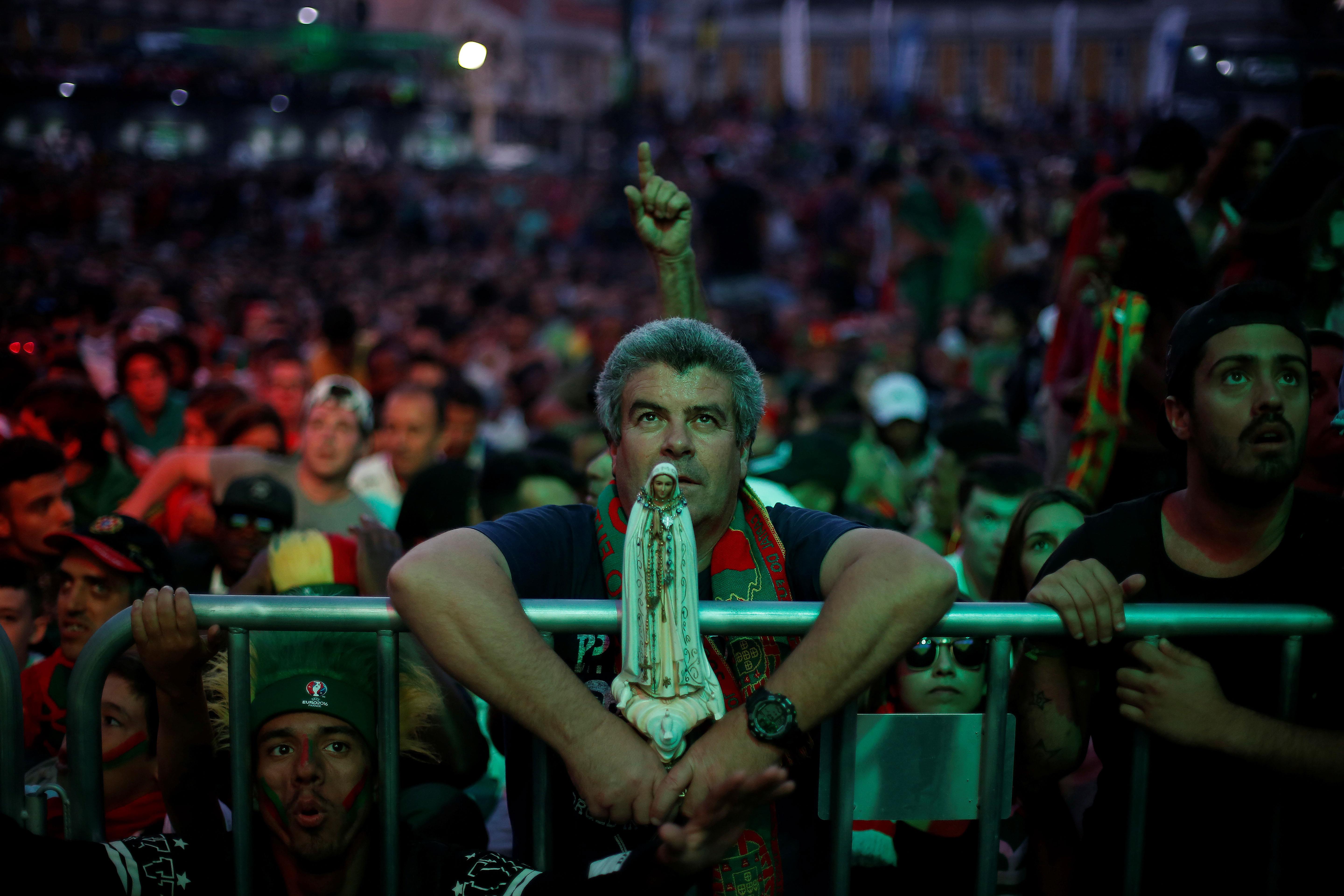 A fan of Portugal holds a statue of Fatima's virgin as they watch the Euro 2016 match between Portug