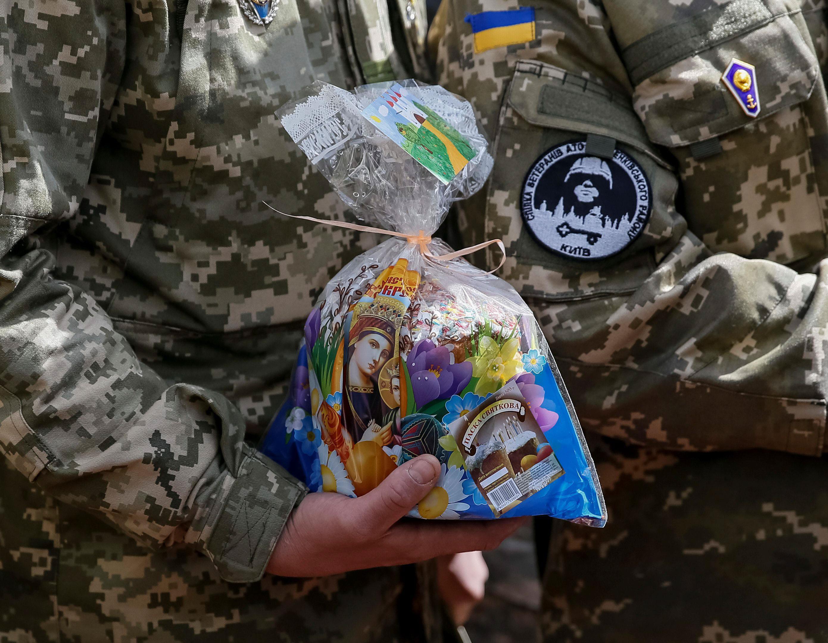 A Ukrainian serviceman holds an Easter cake during a ceremony to bless Easter cakes and eggs in cent