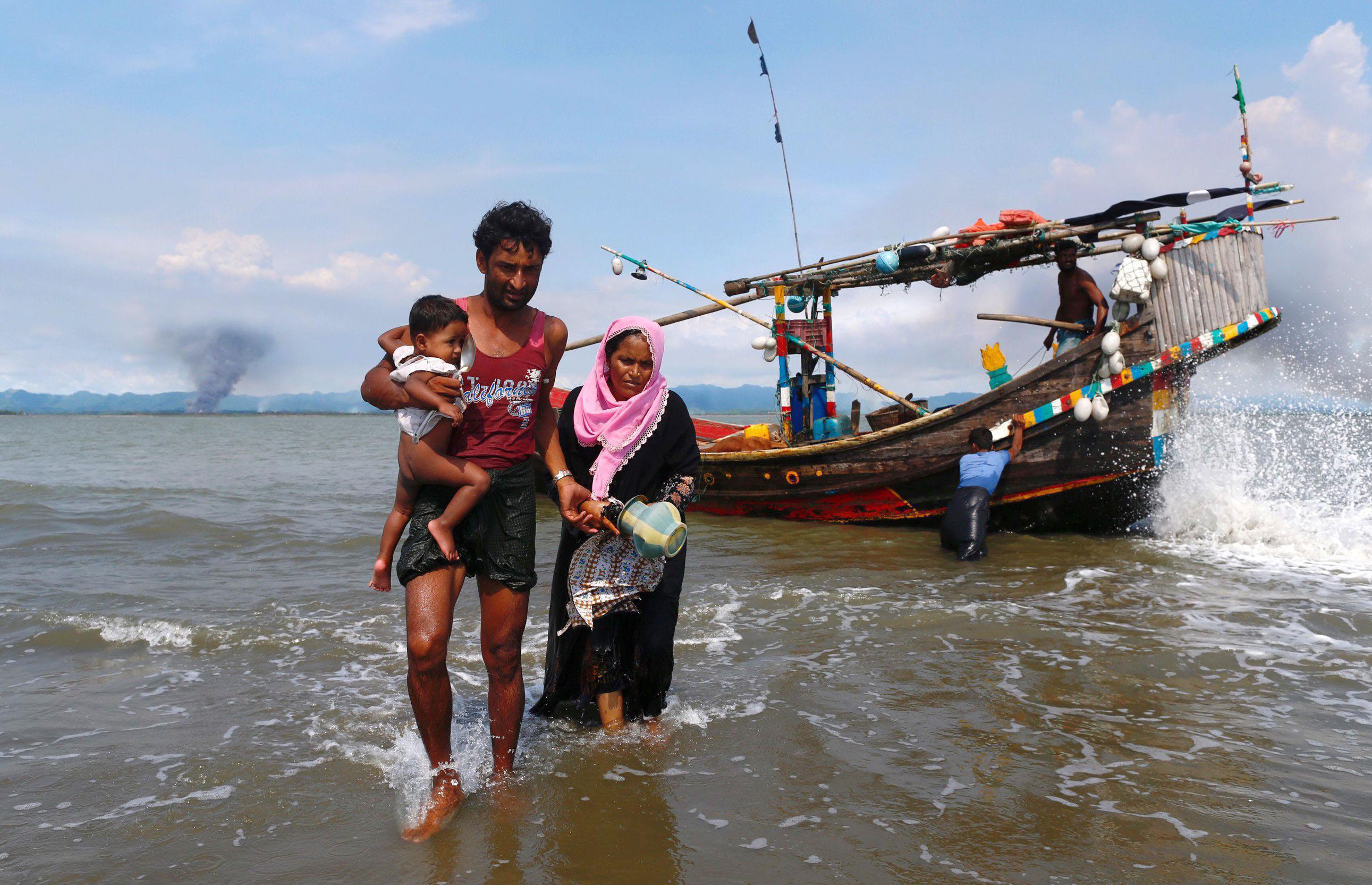 Smoke is seen on Myanmar's side of border as Rohingya refugees get off from a boat after crossing th