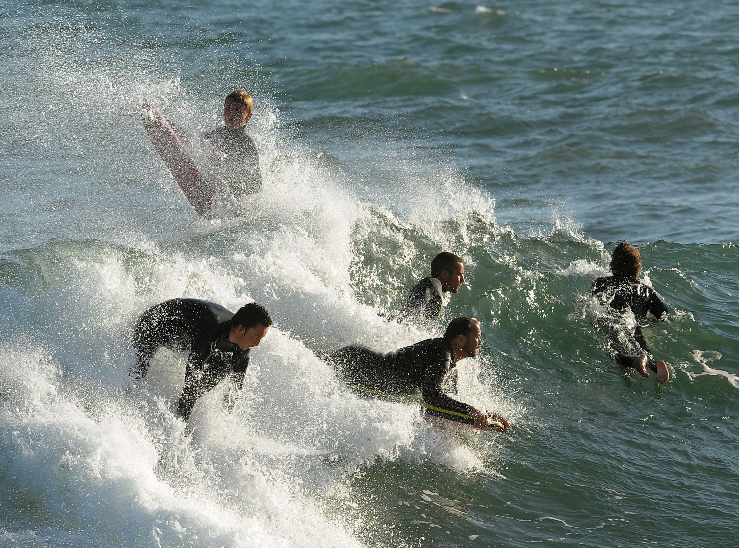 Surferzy i boogie boarderzy wsiadają na falę w Newport Beach, w Kalifornii