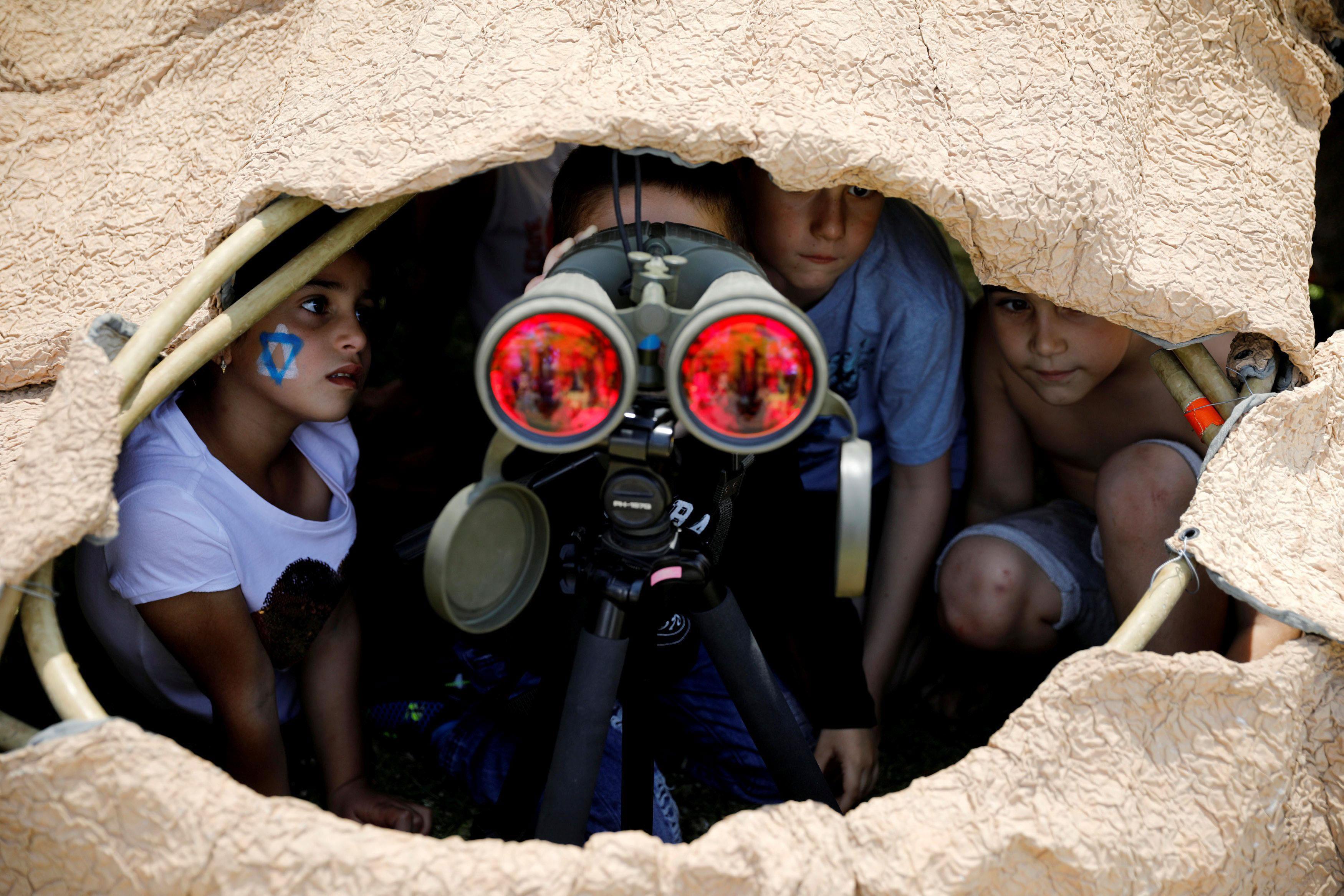 Israeli children look through binoculars during a display of Israeli Defense Forces equipment and ab