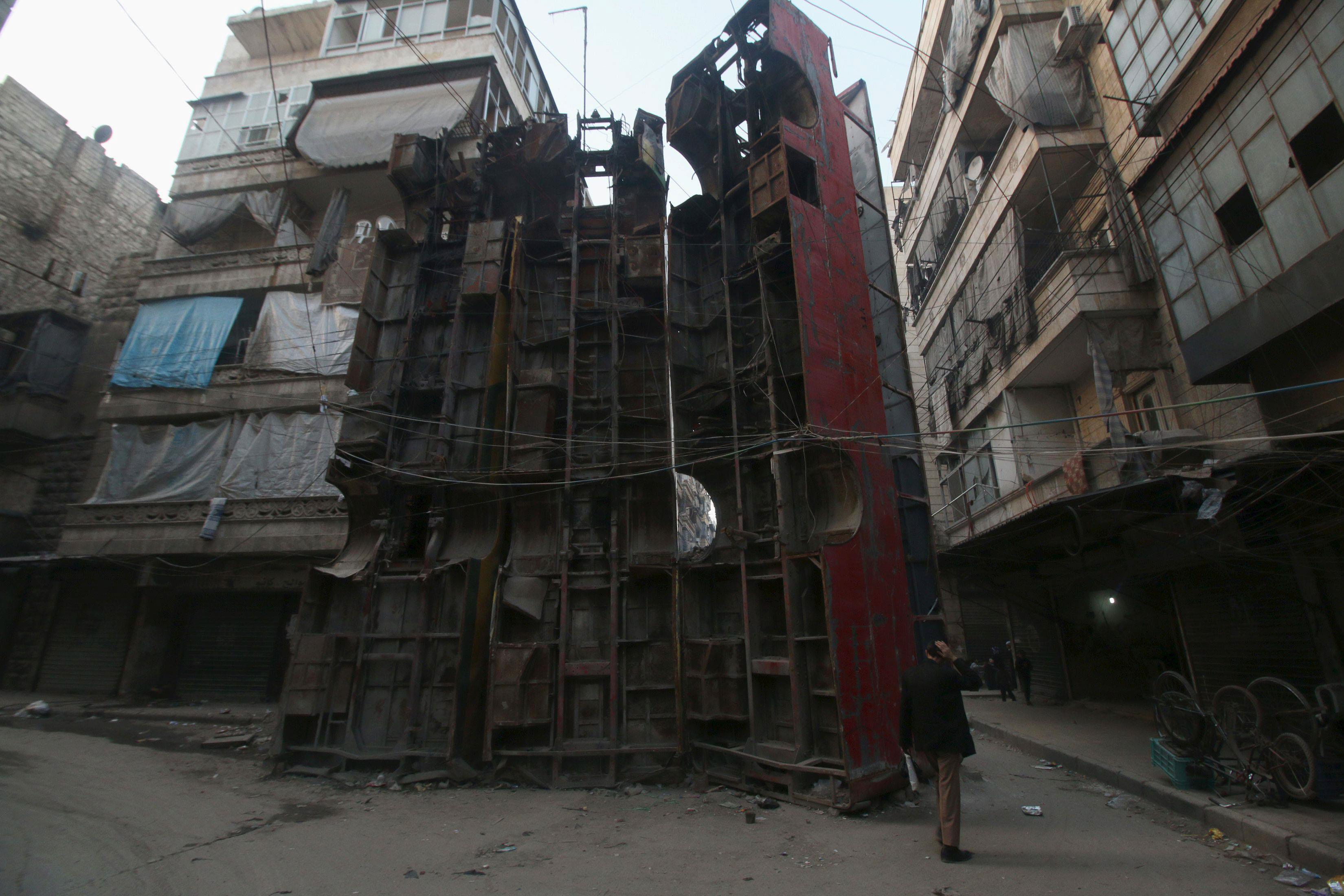 Civilians walk near upright buses barricading a street, in Aleppo's rebel-controlled Bustan al-Qasr 