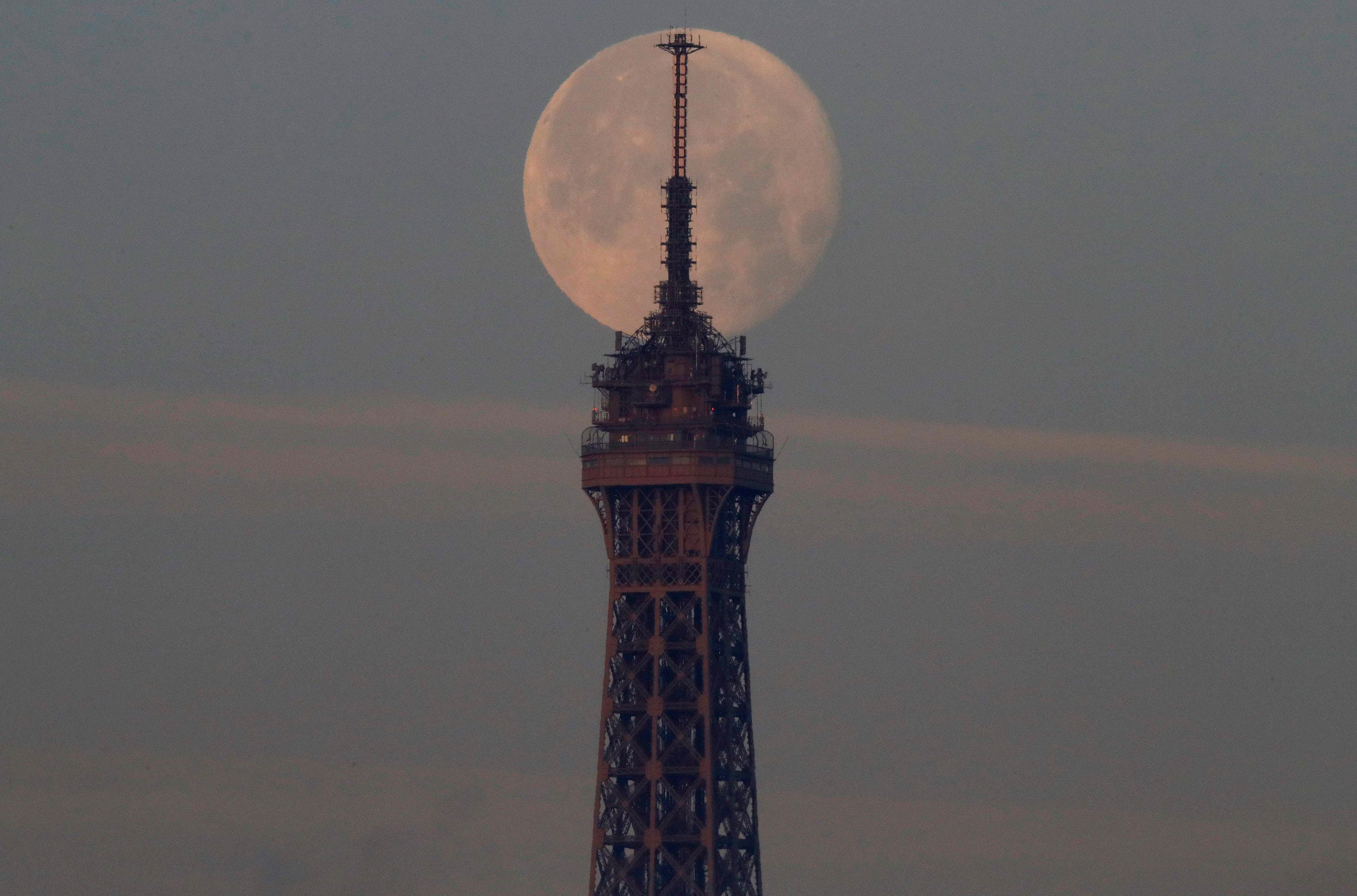 The moon sets over the Eiffel Tower in Paris