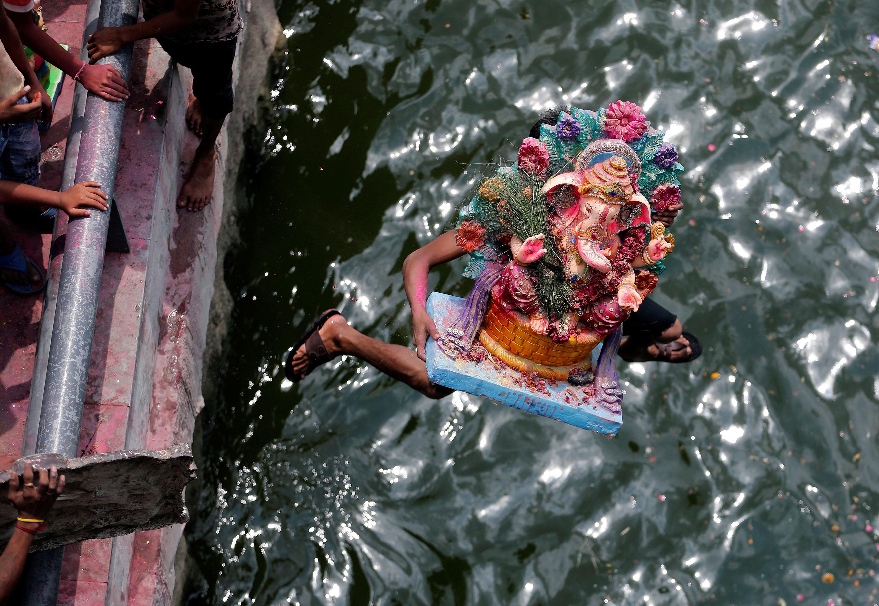 A devotee carrying an idol of the Hindu god Ganesh, the deity of prosperity, jumps into the Sabarmat