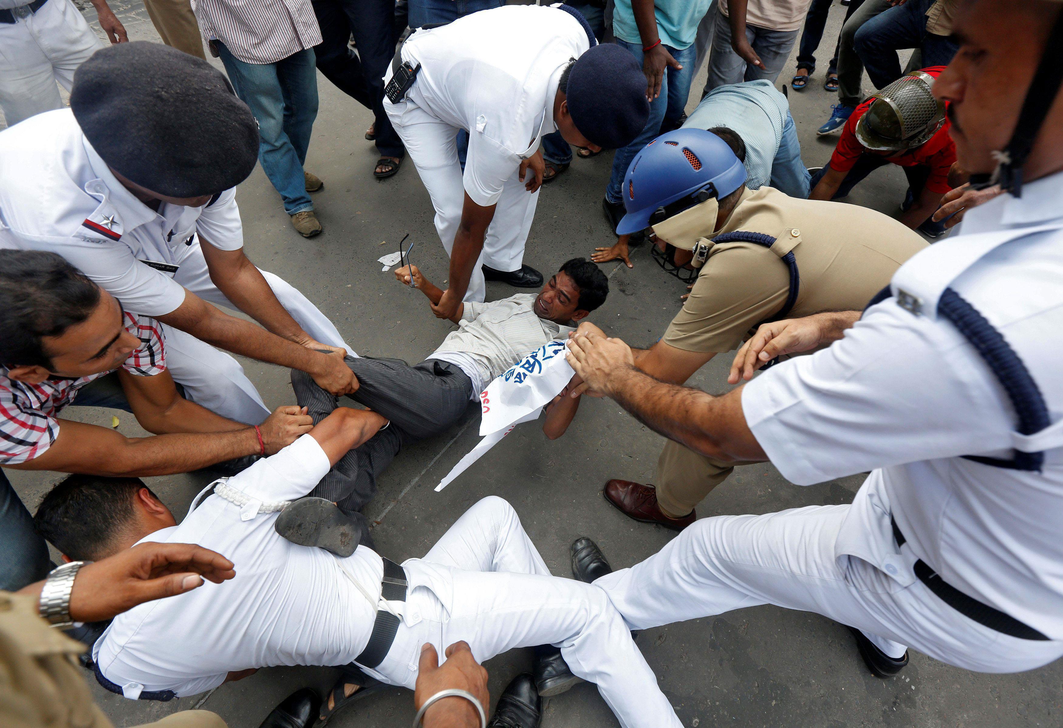 Police officers try to detain a demonstrator during a protest against what the demonstrators said wa