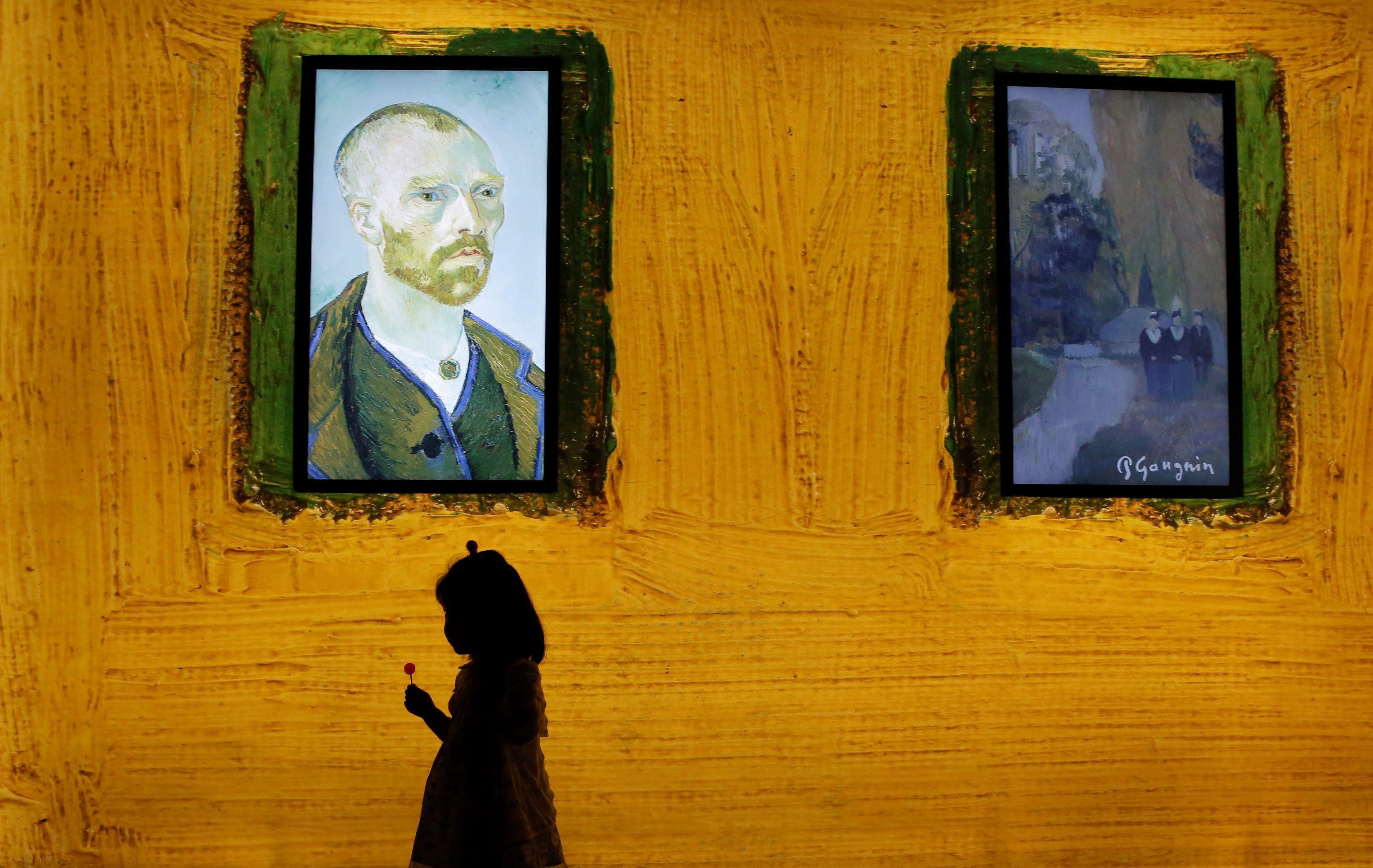 A girl walks past a display at the world premiere of 'Meet Vincent van Gogh' exhibition in Beijing