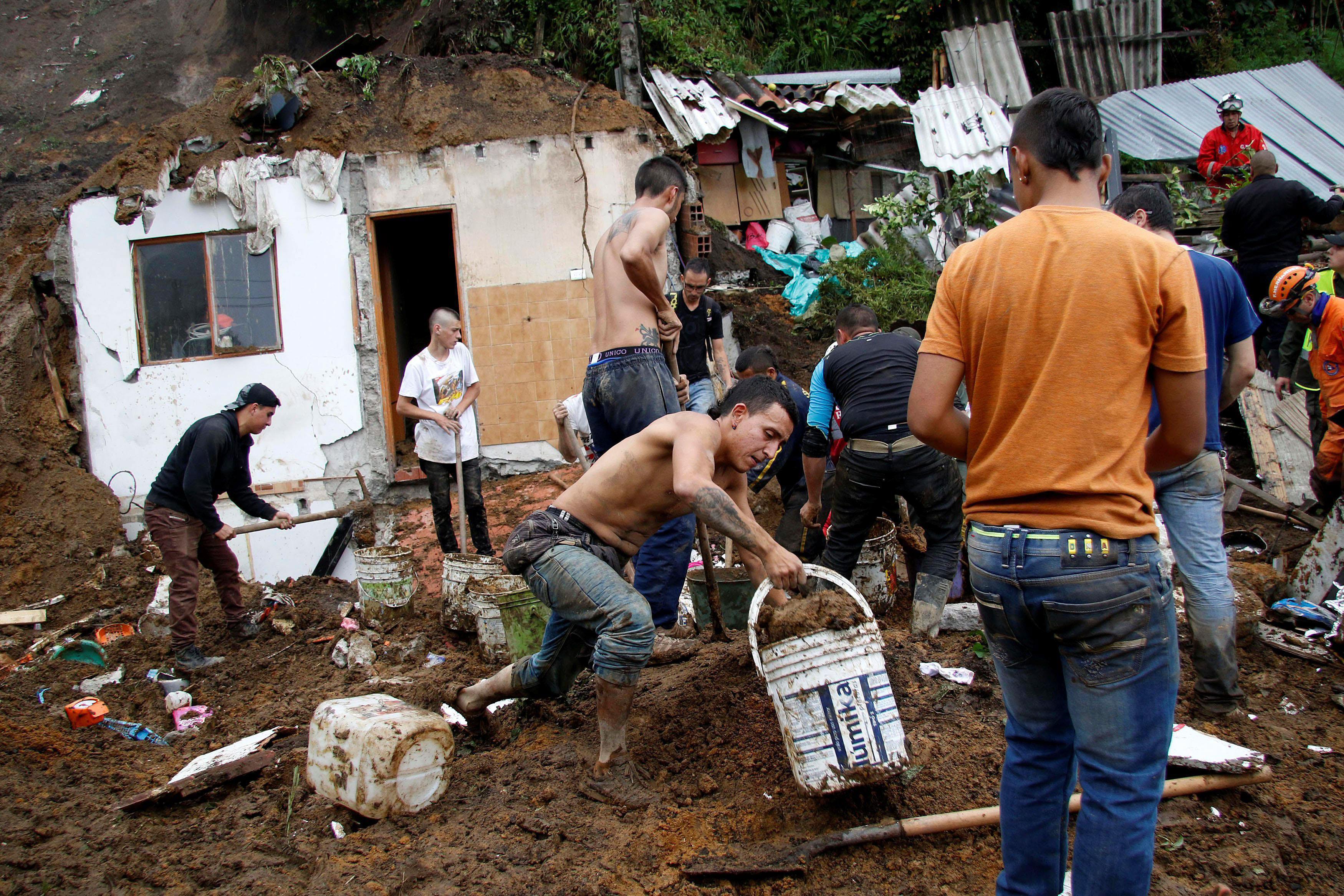 People and rescue agencies look for bodies in a destroyed area after mudslides, caused by heavy rain