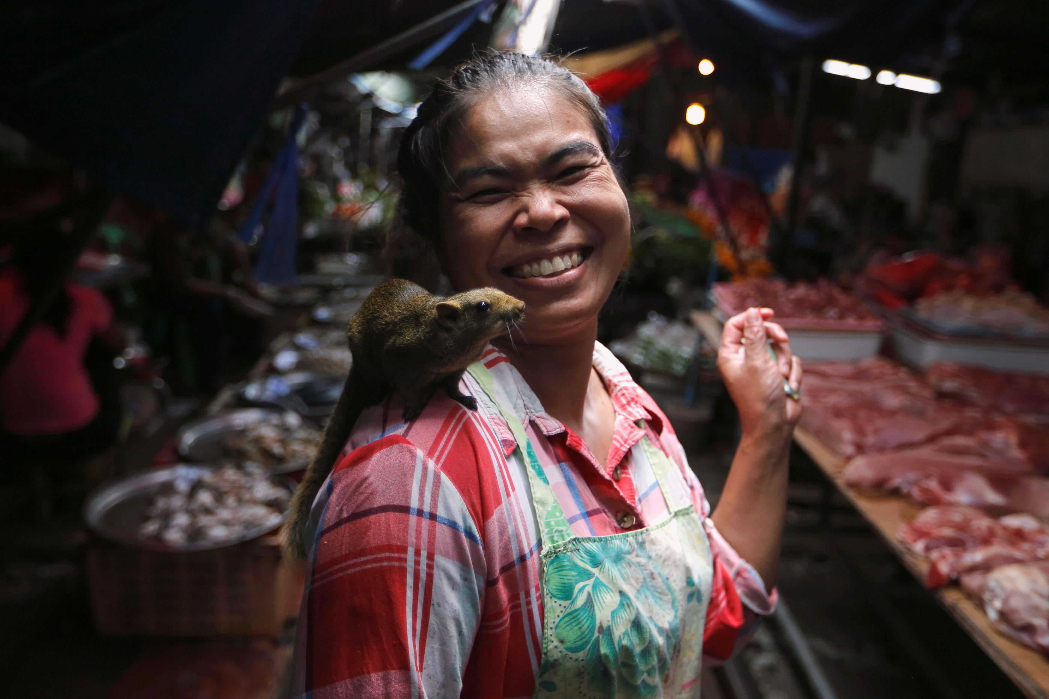 A woman walks with a squirrel on her shoulder at Maeklong market at the outskirts of Bangkok