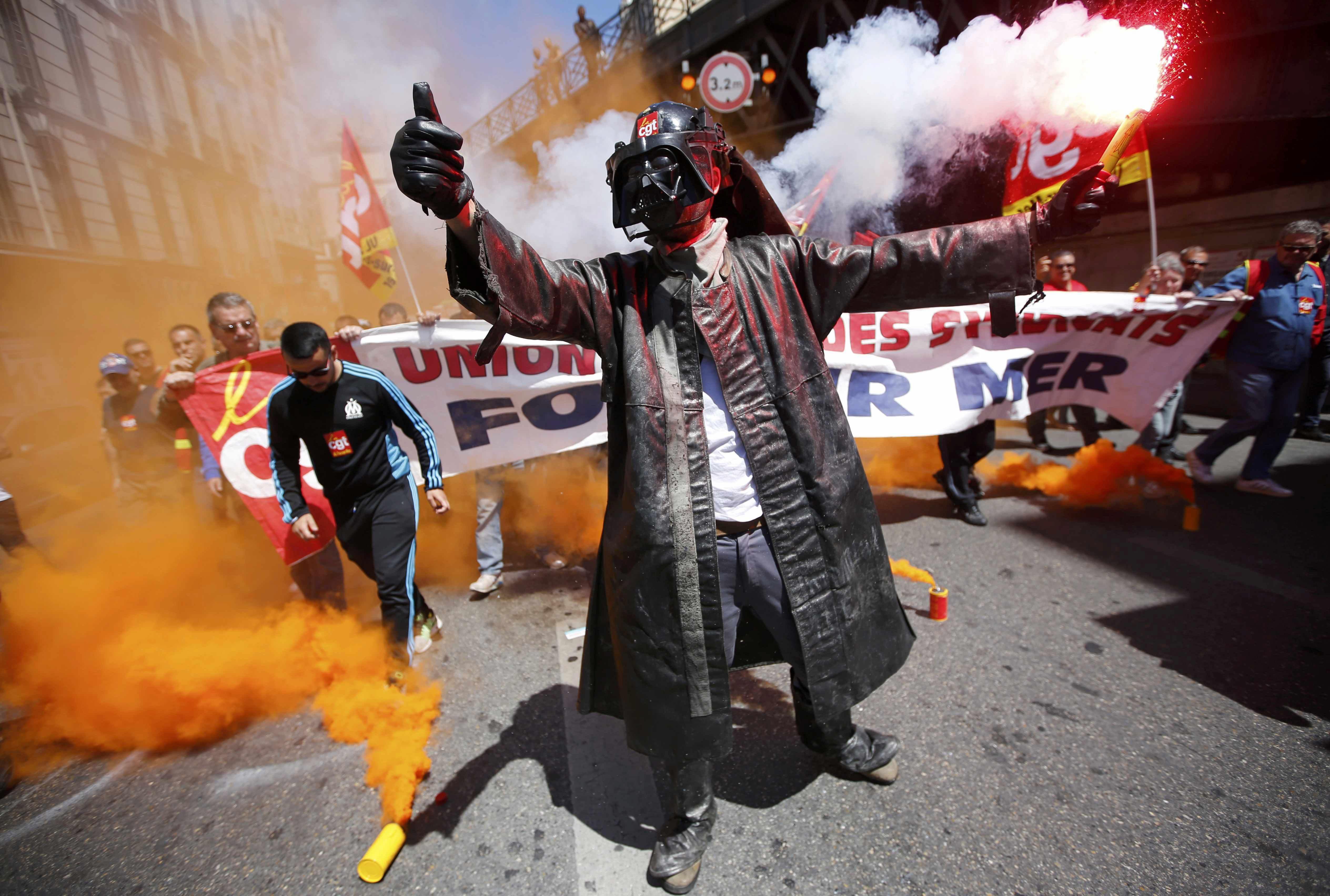 An Arcelor Mittal steel worker dressed in a protective work suit holds flares during a demonstration