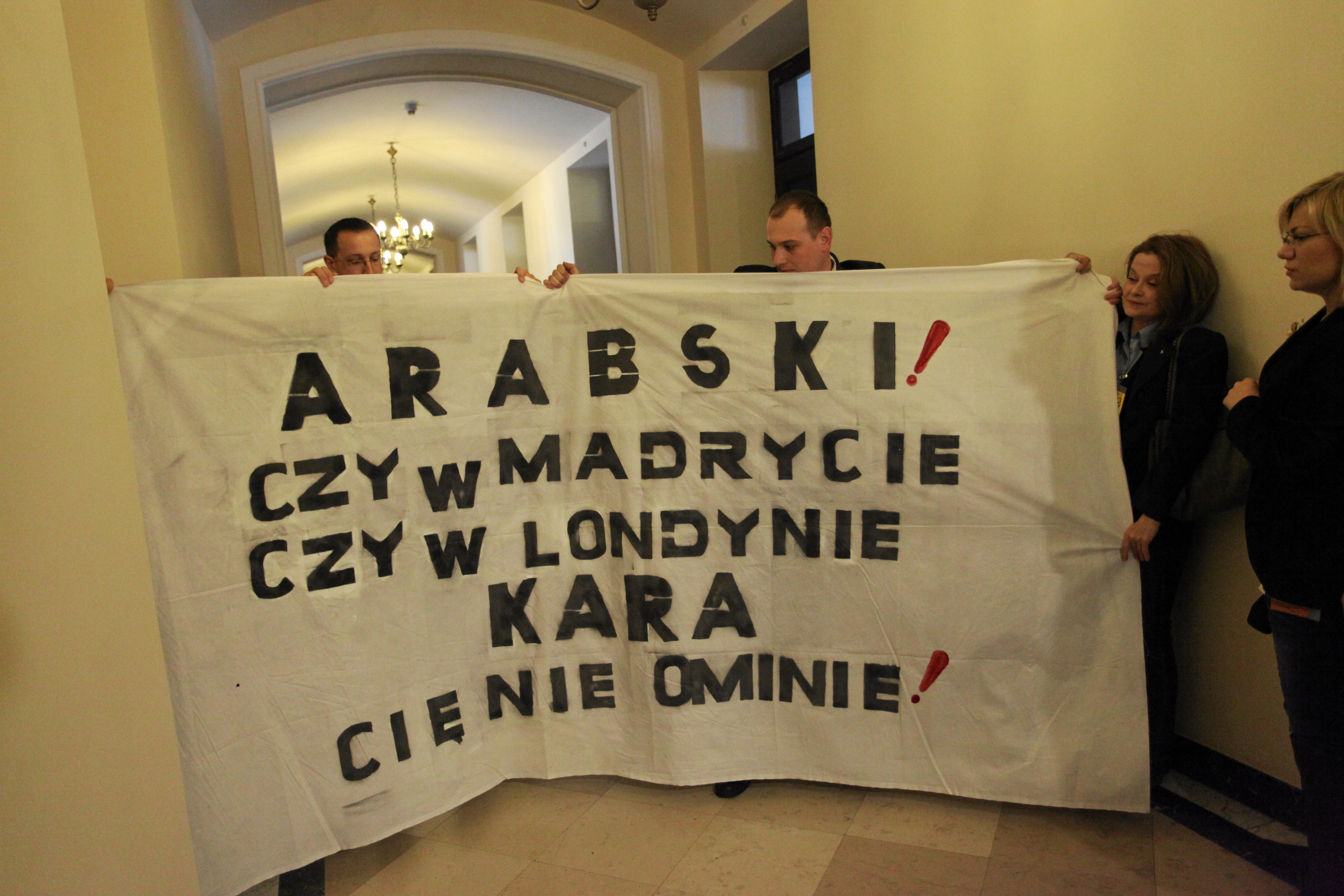 Grupa kilku osób trzymała w rękach transparent z hasłem: