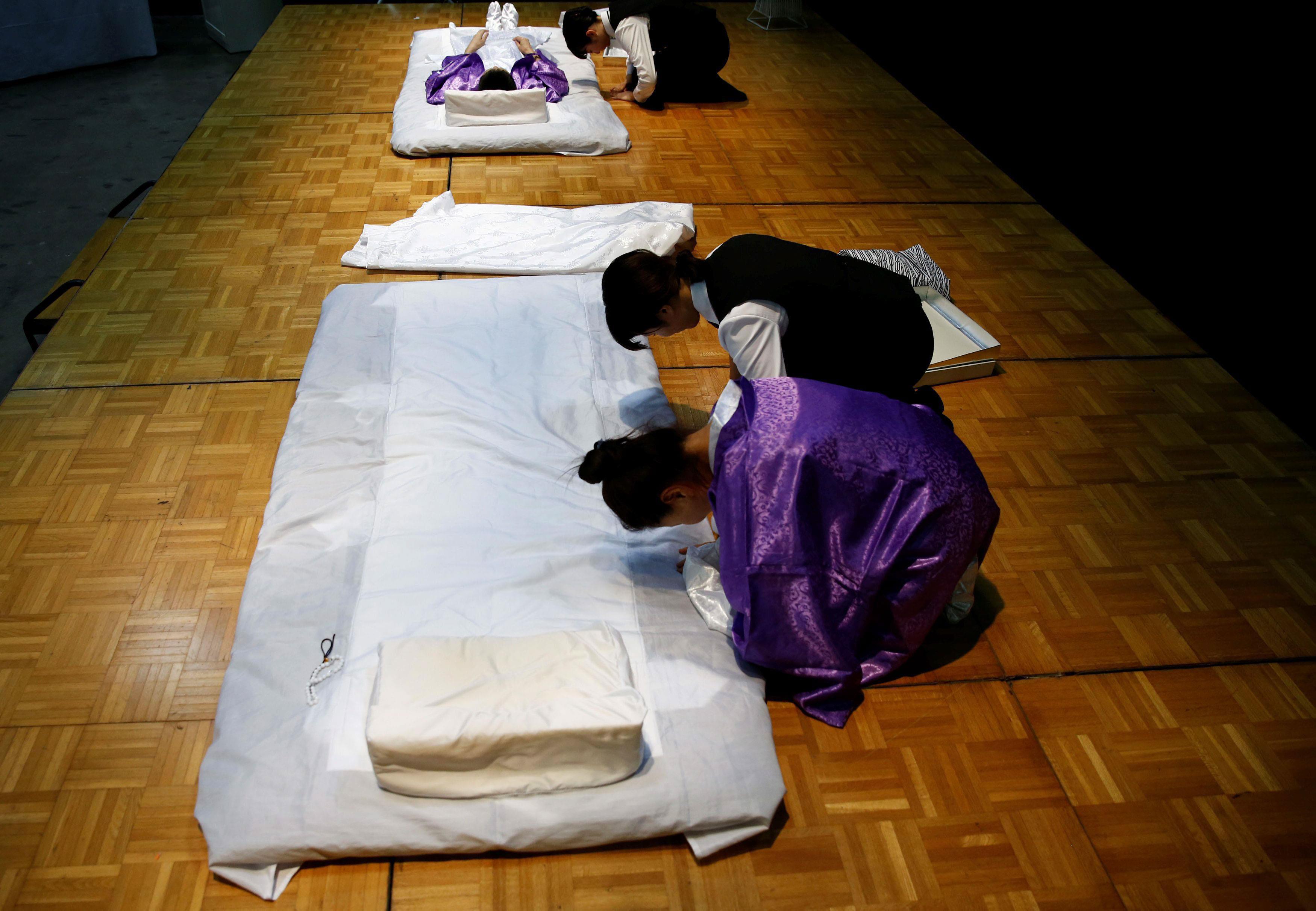 A funeral undertaker and a model greet spectators during an encoffinment competition at Life Ending 