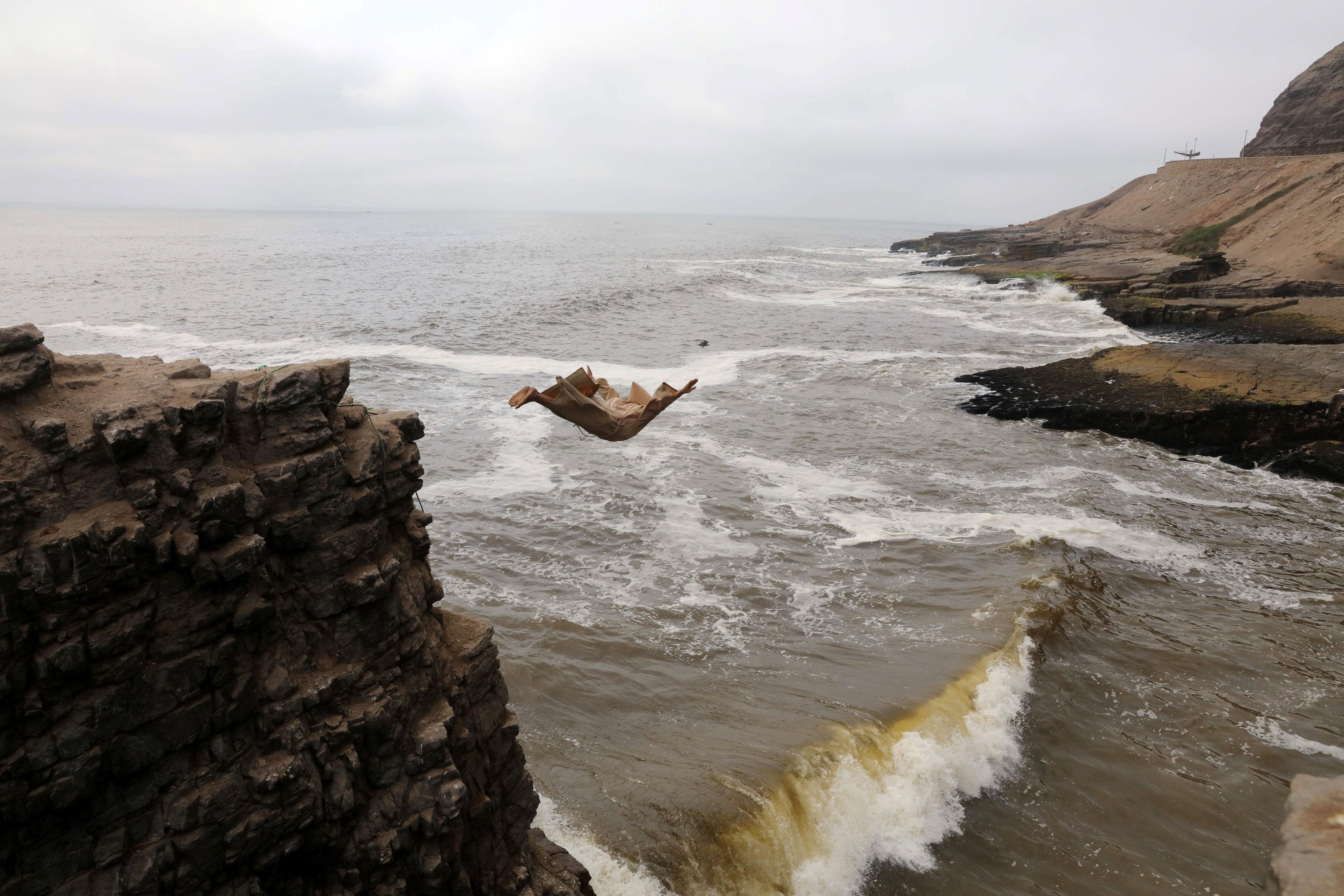 Fernando Jesus Canchari, dressed as a friar jumps from a 13-meter high cliff along Herradura Beach i