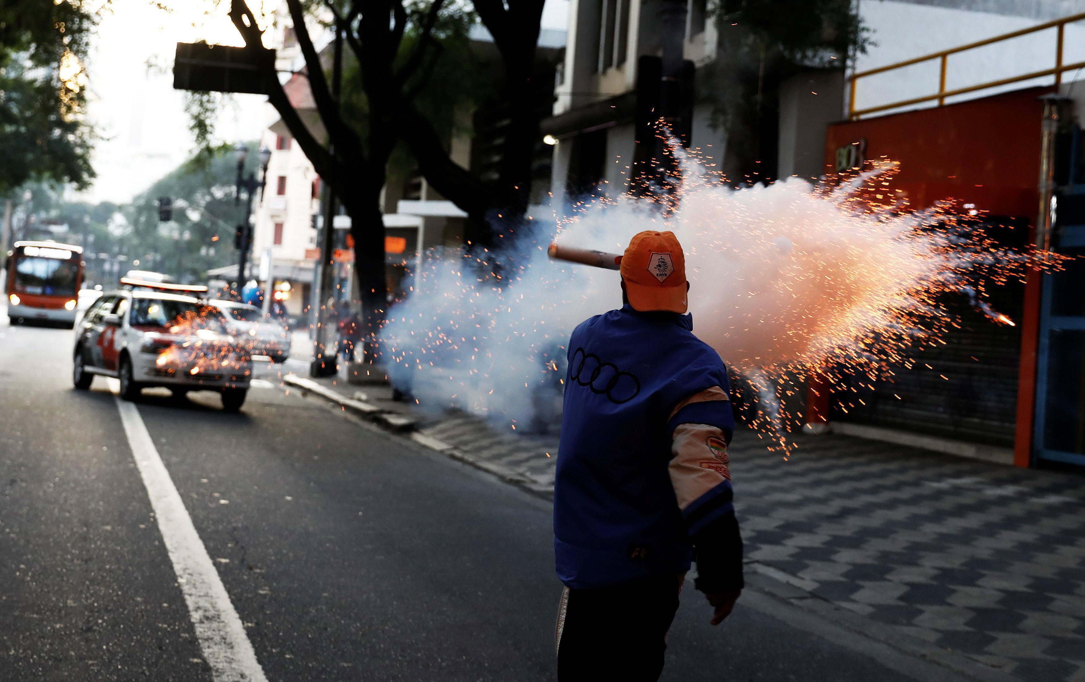 Member of Brazil's Movimento dos Sem-Teto (Roofless Movement) sets off a flare bomb against riot pol