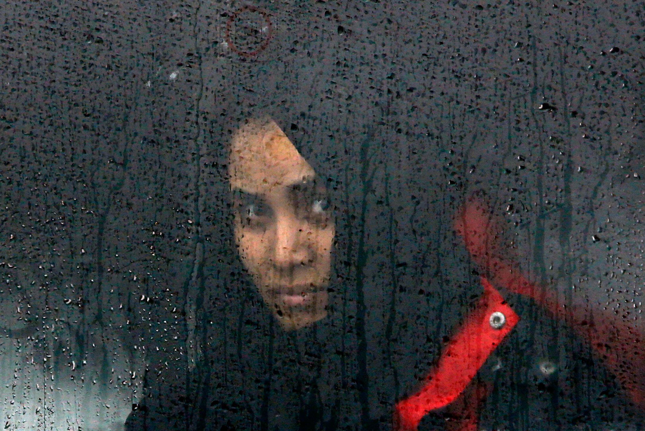 A migrant looks through a train window as migrants and refugees wait for their train to depart to Sl