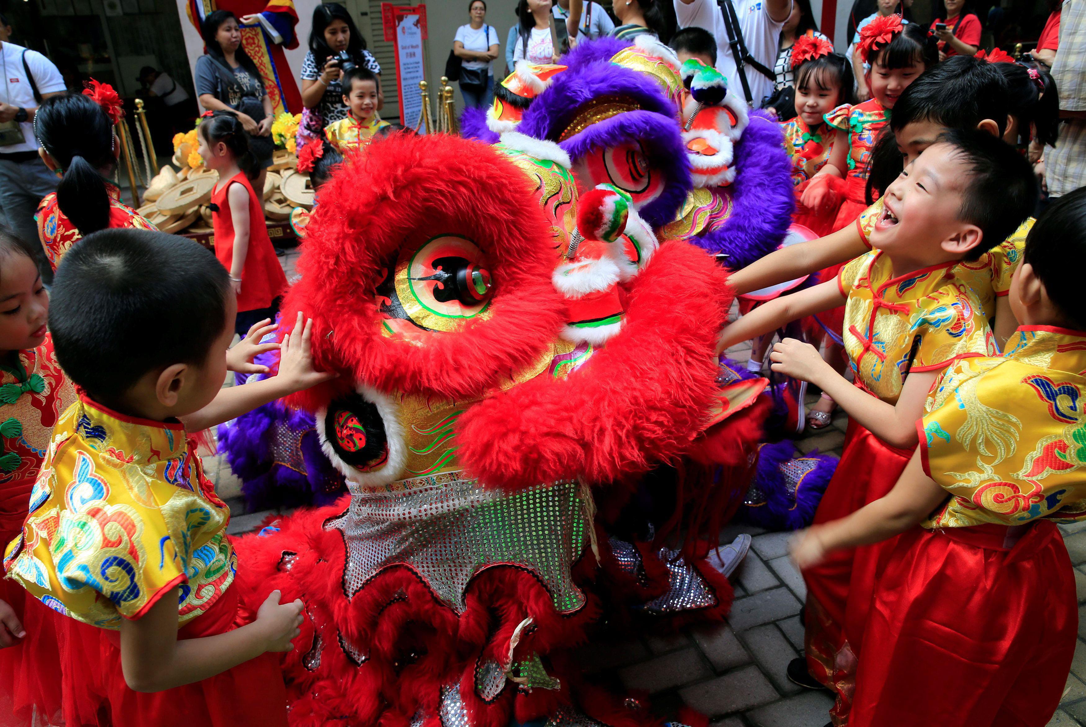 Filipino-Chinese students play with Lion dancers after performing a traditional dance ahead of the L