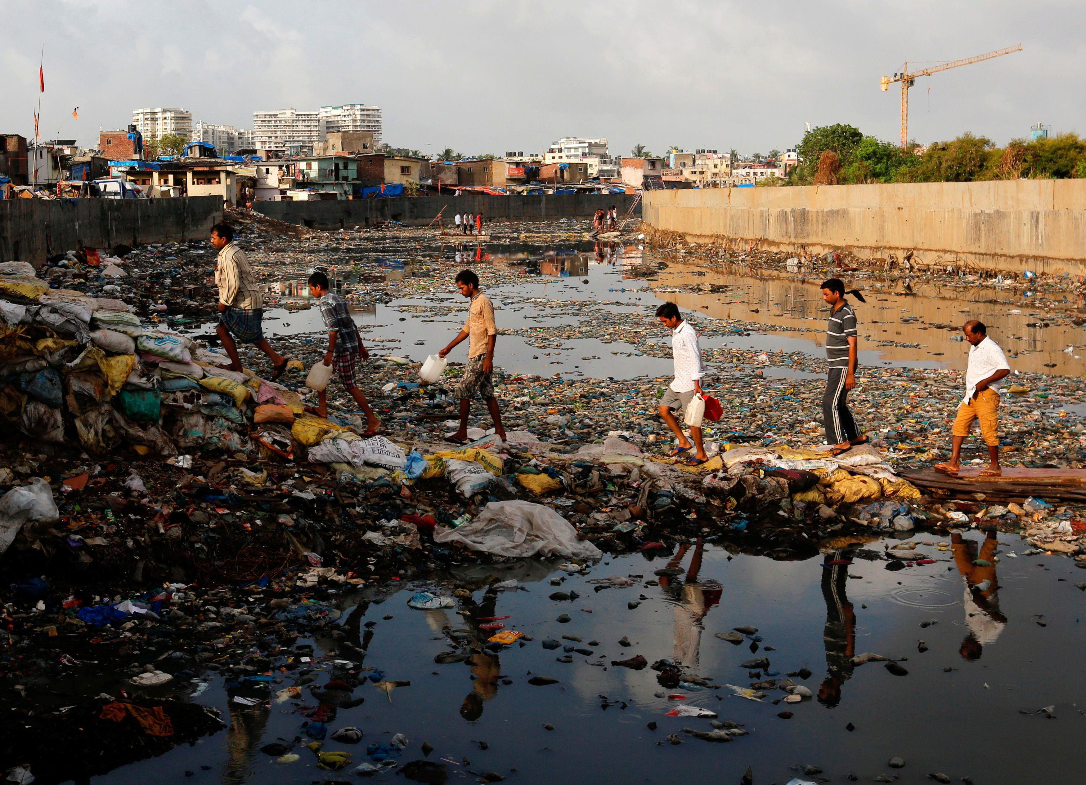 Residents cross a polluted water canal at a slum on the World Environment Day in Mumbai