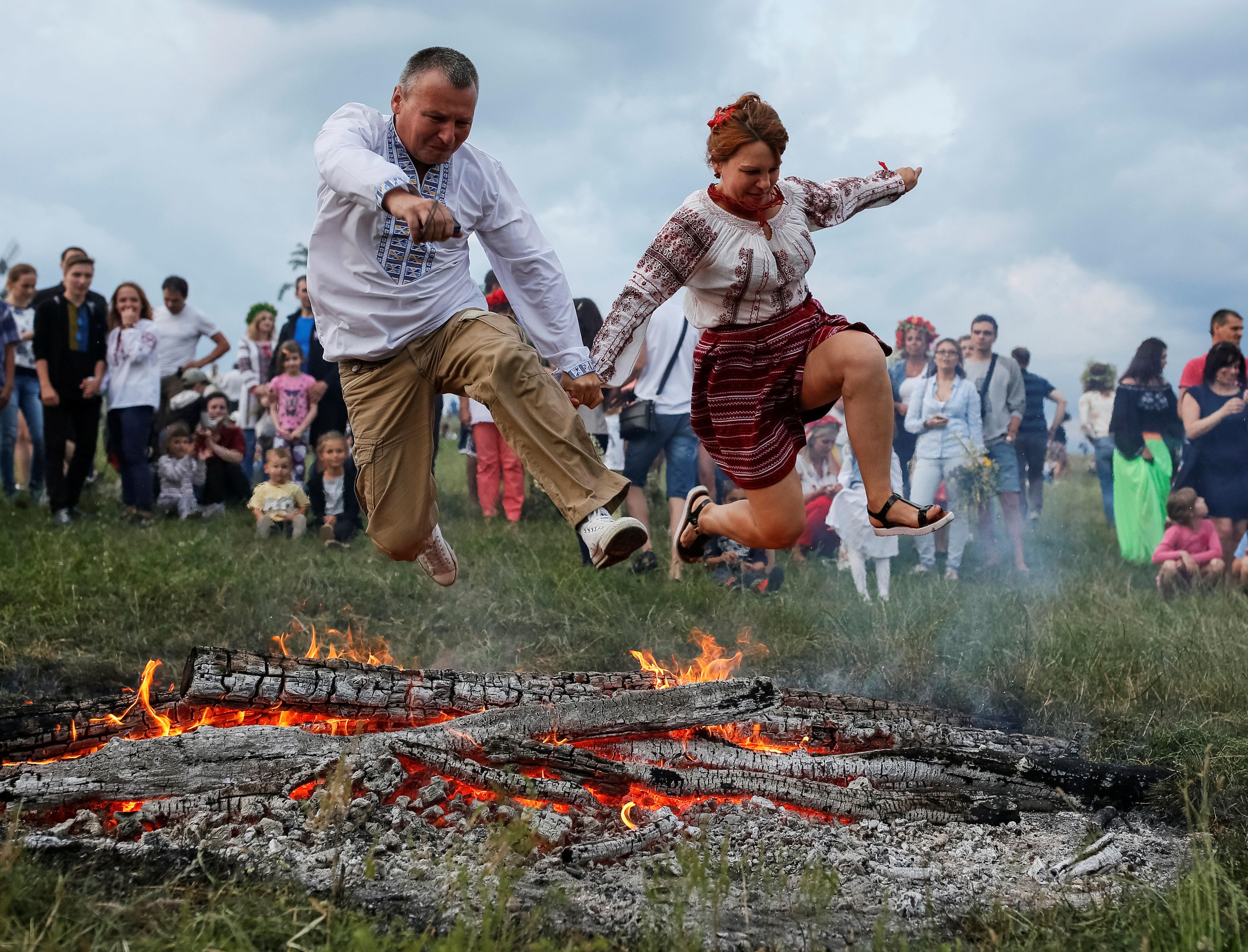 People jump over a campfire during a celebration on the traditional Ivana Kupala holiday in Kiev